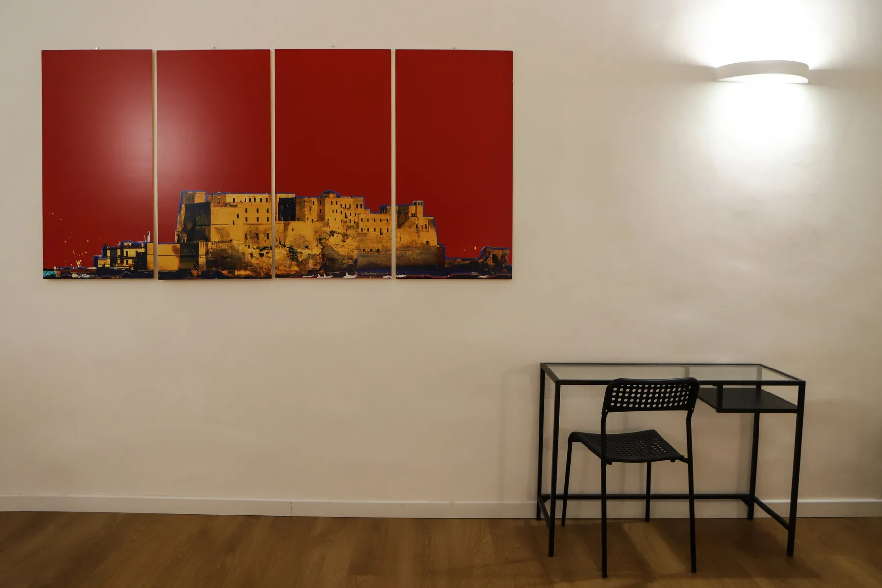 Una habitación con pocos muebles tiene una obra en la pared sobre una mesa pequeña y una silla.