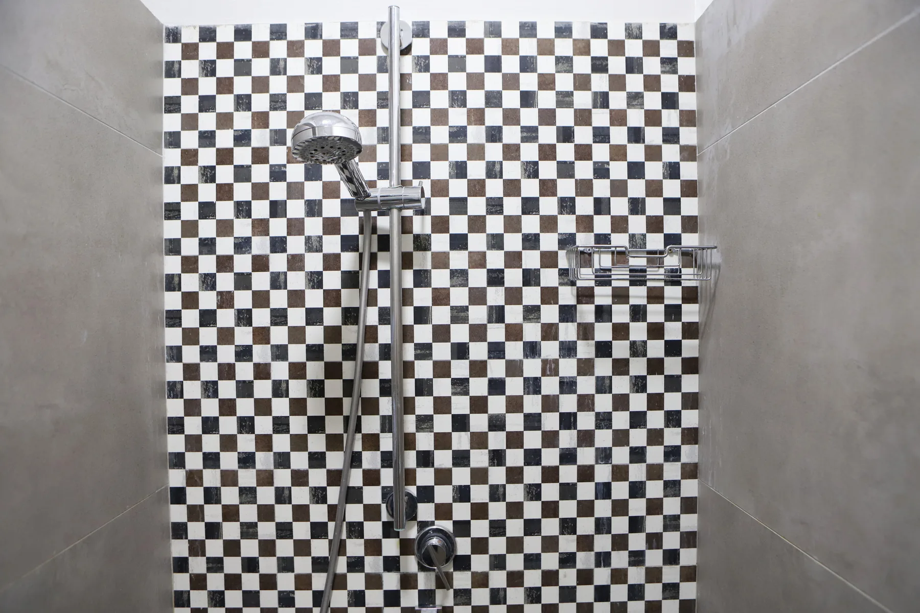 Una ducha con cabezal de mano y azulejos a cuadros.
