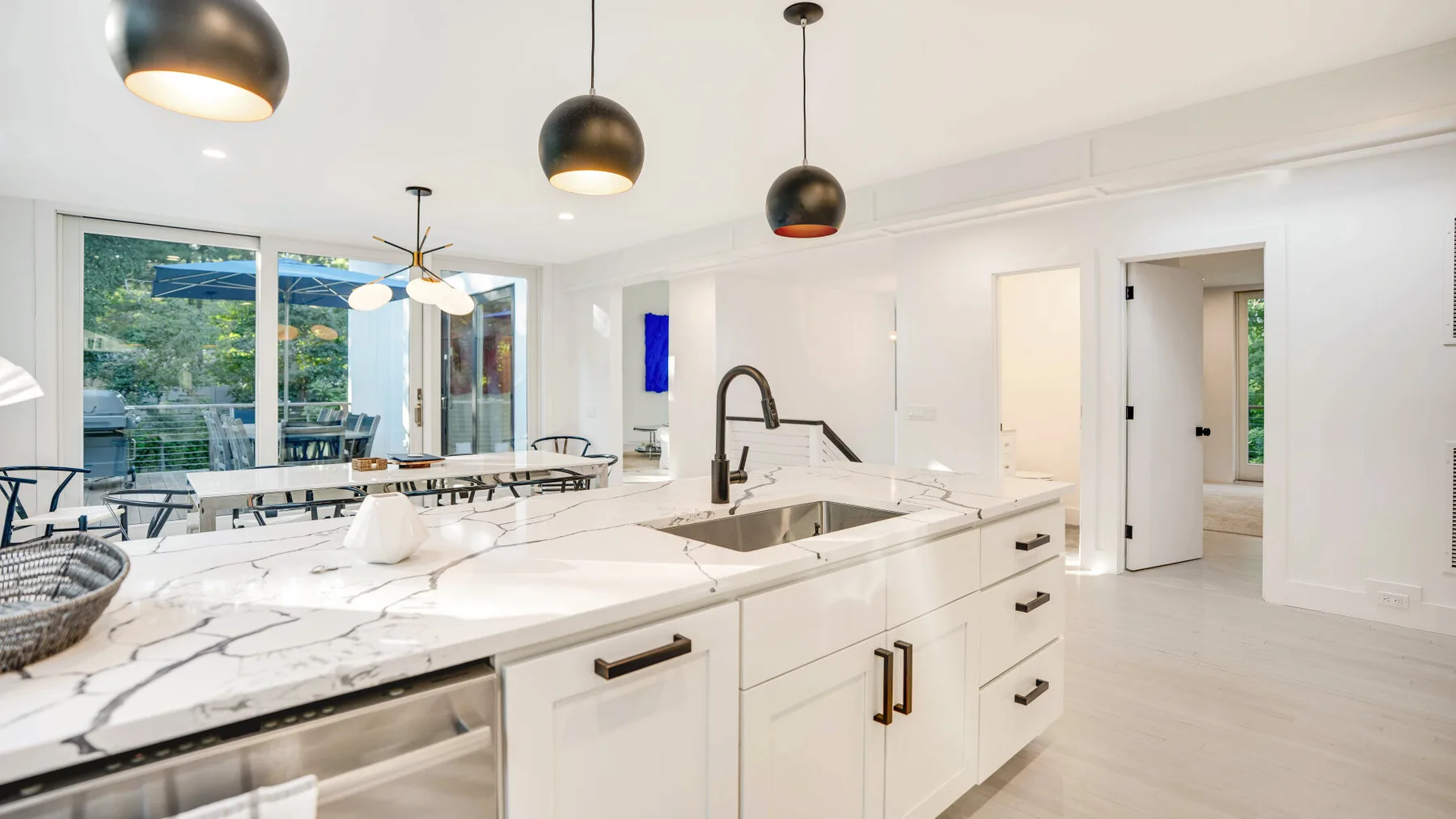 Una cocina luminosa con una gran isla de acabado jaspeado y lámparas colgantes.