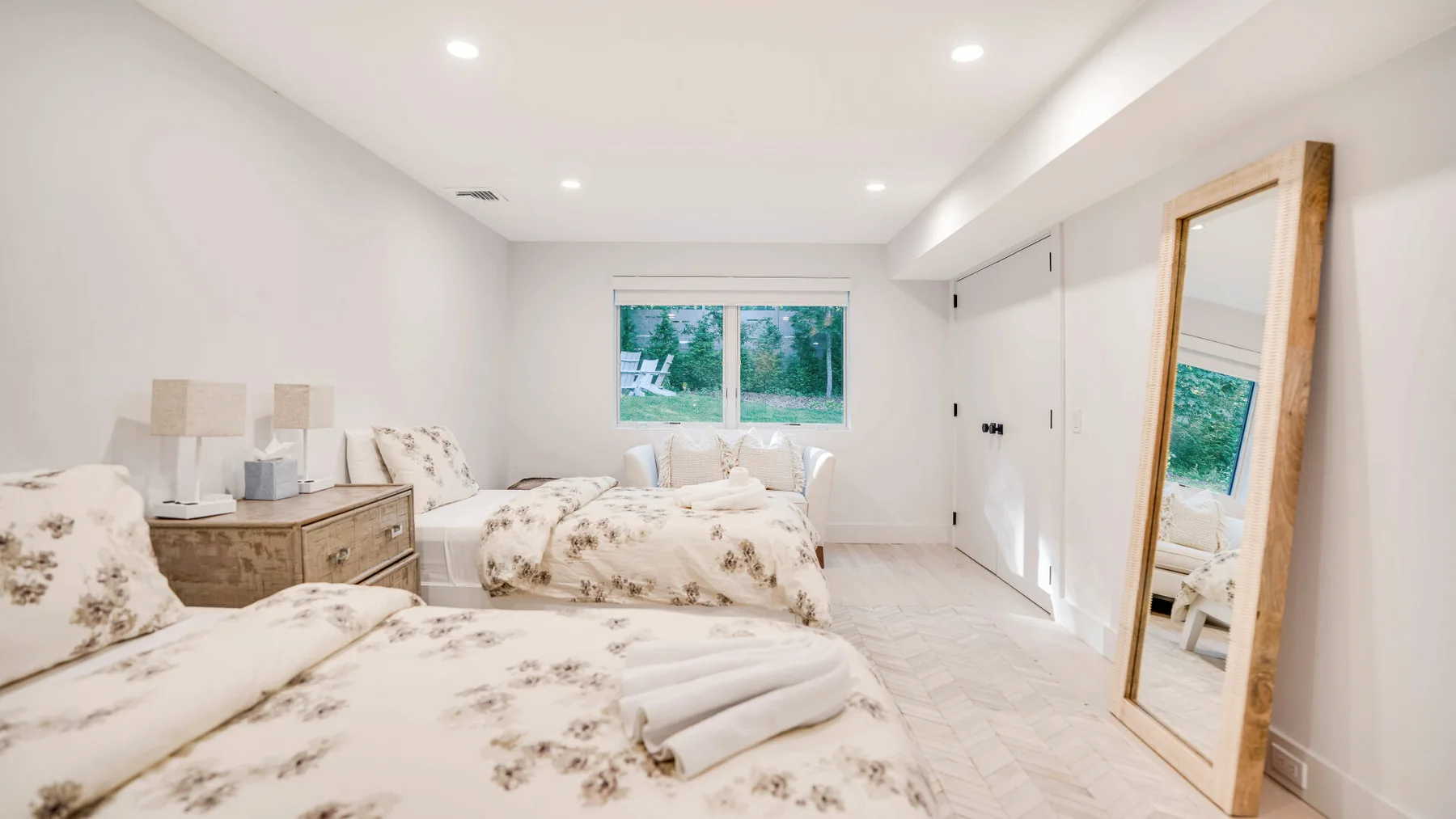 Un dormitorio luminoso con ropa de cama estampada y un espejo de cuerpo entero.