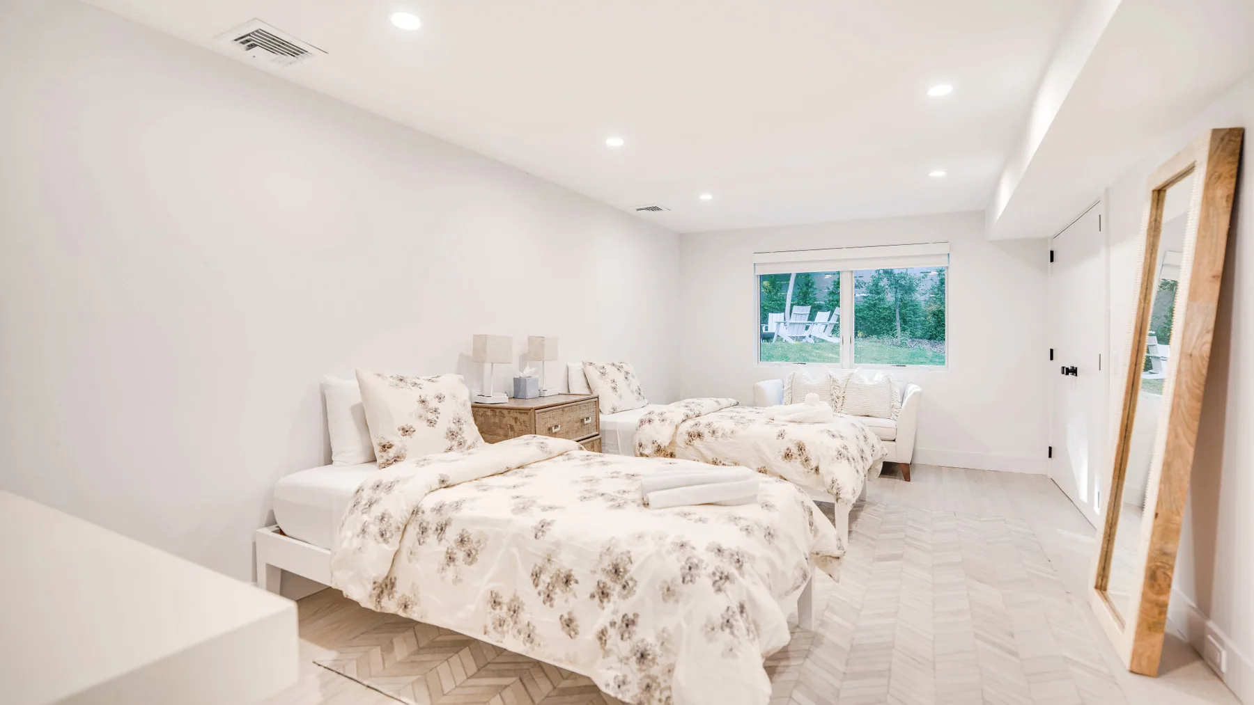 Un dormitorio luminoso con ropa de cama floral y una ventana grande.