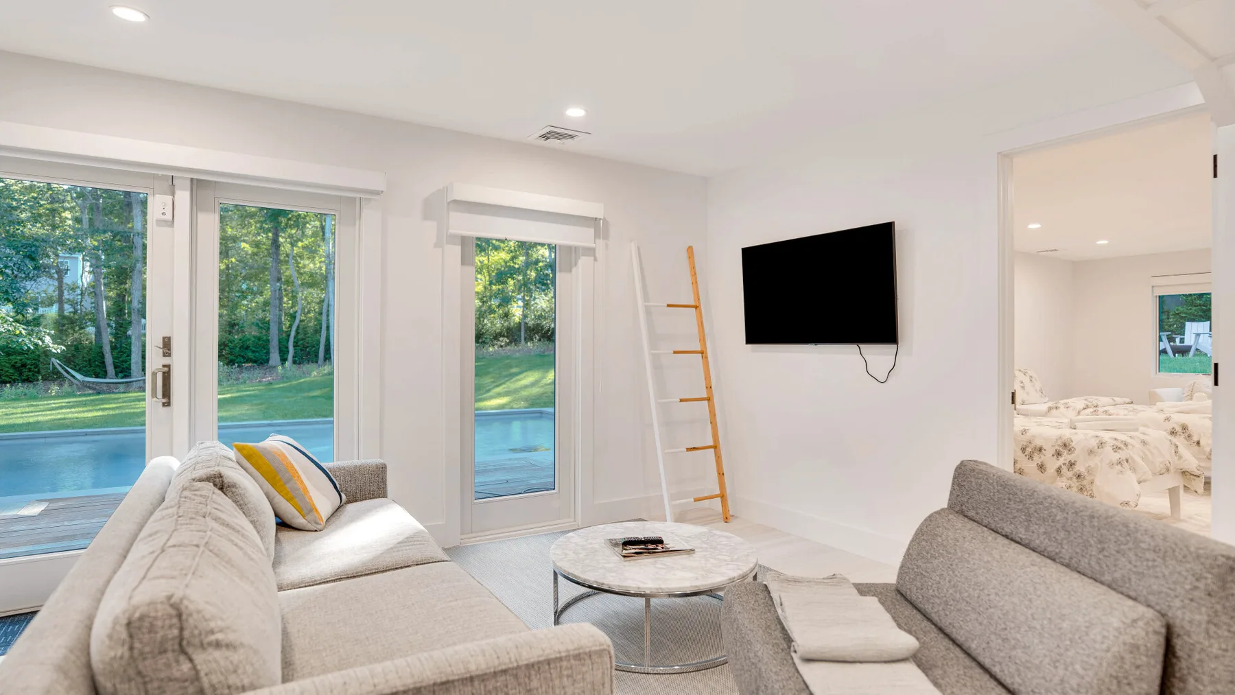 Una sala luminosa con asientos, un televisor en la pared y ventanas grandes.
