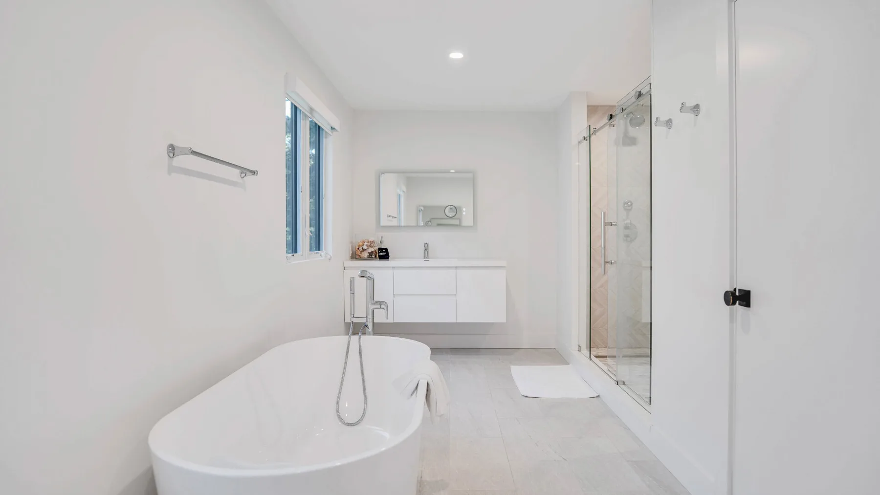 Un baño luminoso con una bañera exenta y una ducha de vidrio.