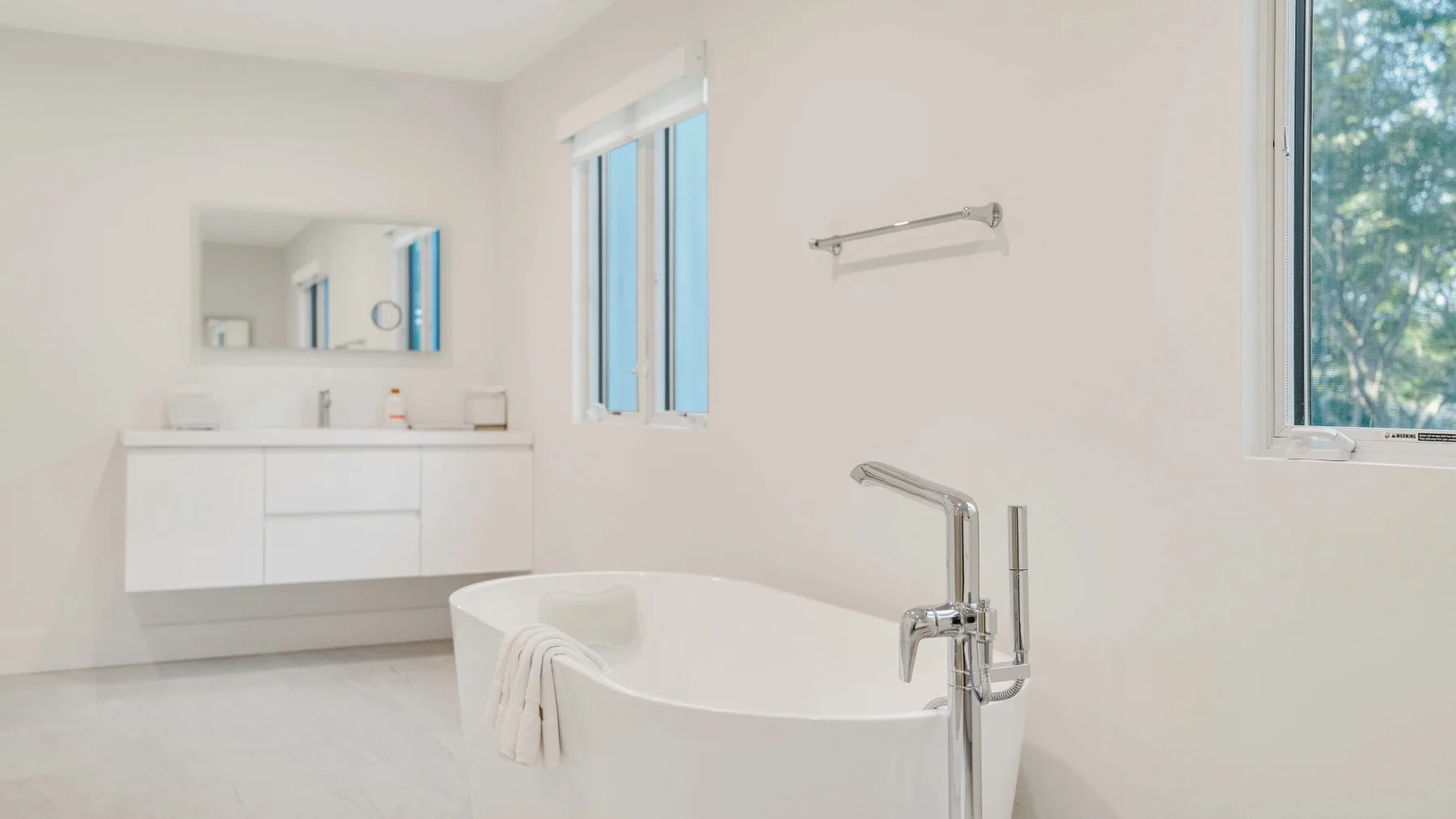 Un baño luminoso con una bañera exenta y un lavabo con mueble.