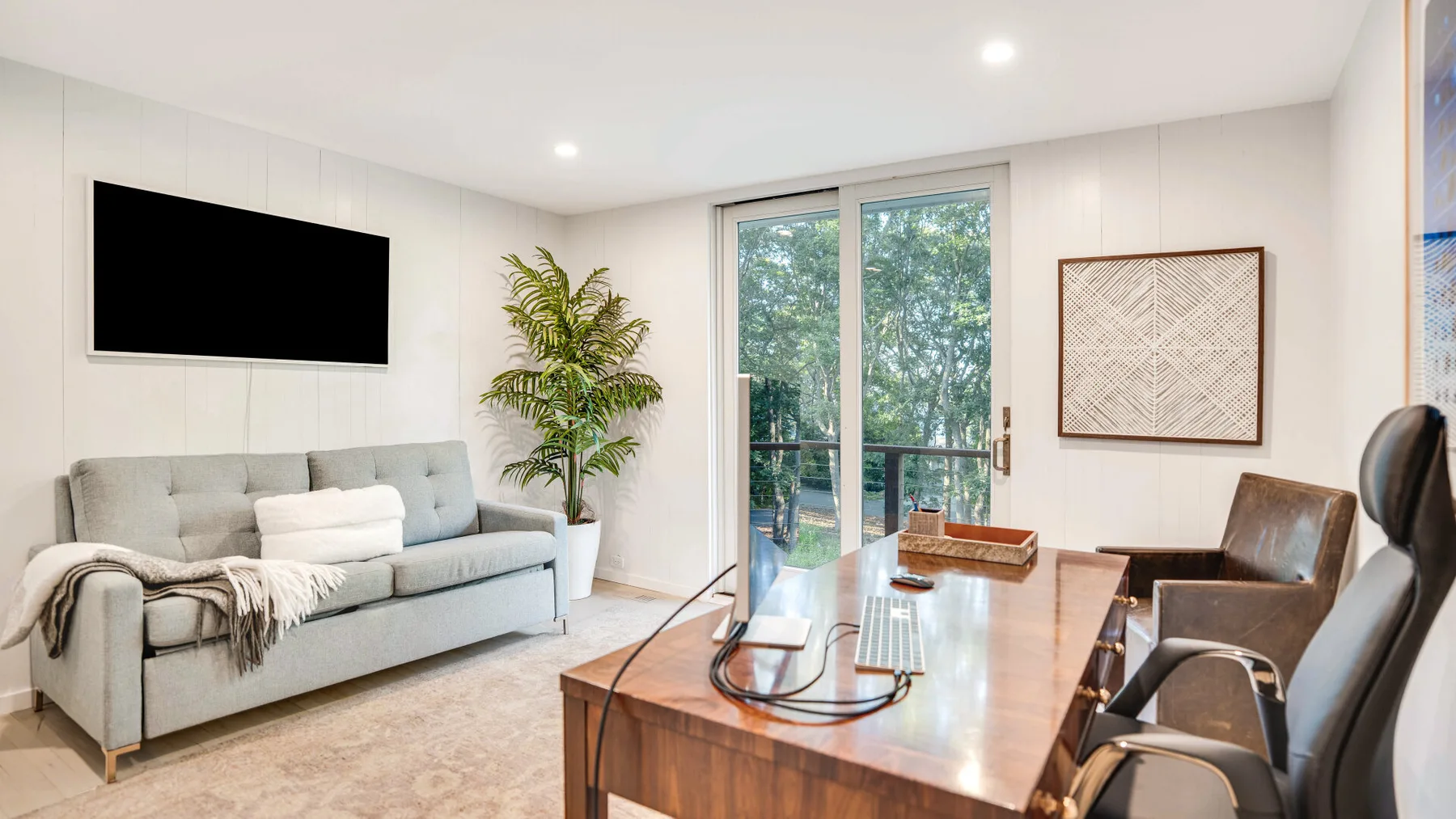 Una sala luminosa con asientos, una mesa de centro y puertas de vidrio hacia la vegetación.