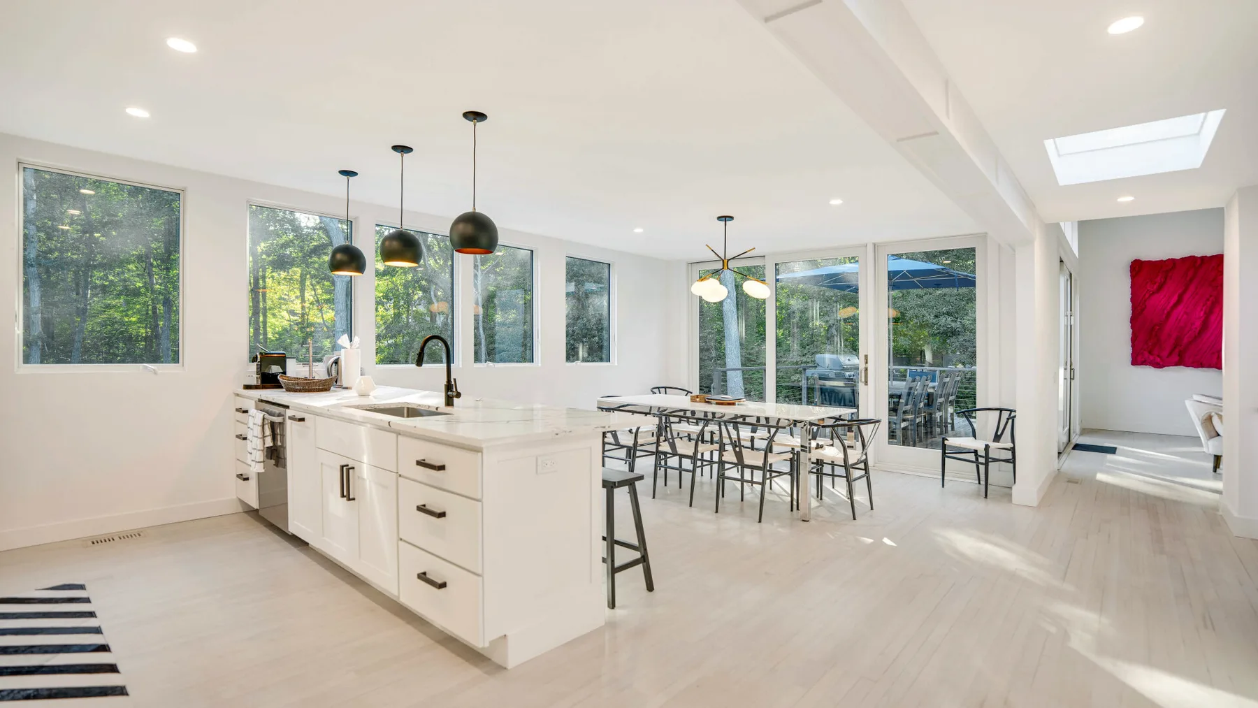 Una luminosa cocina abierta con comedor, grandes ventanas y una isla central.