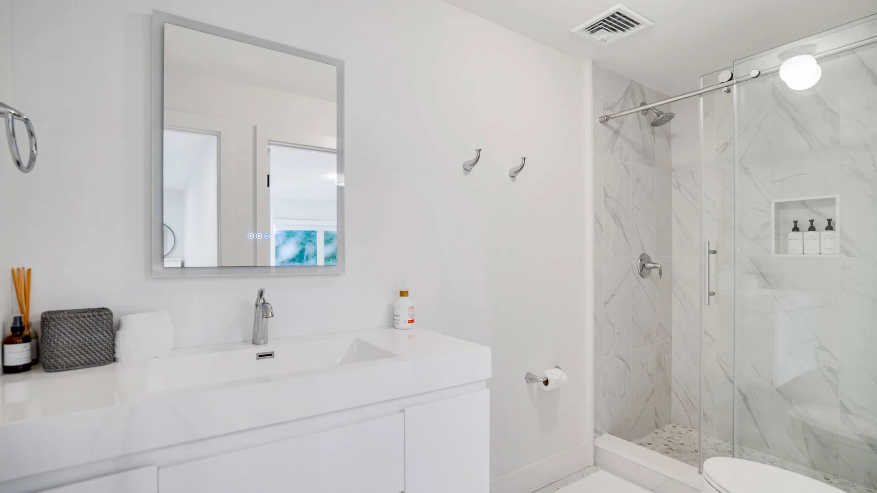 Un baño luminoso con un tocador amplio y una ducha con mampara de vidrio.