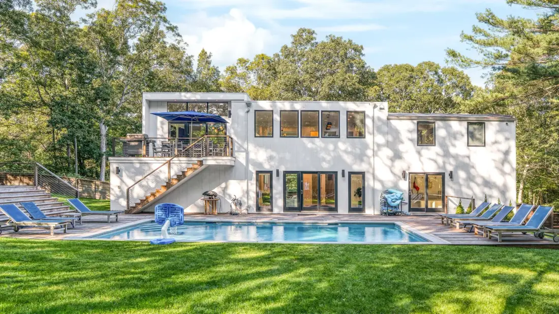 Una casa moderna da a una piscina y un césped verde.