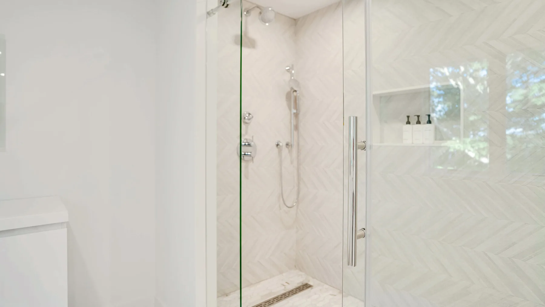 Un baño luminoso con ducha de vidrio y paredes alicatadas.