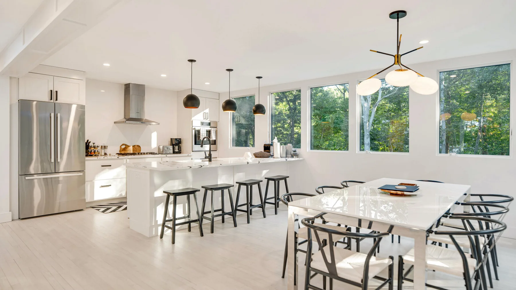 Una luminosa cocina-comedor de planta abierta con una mesa grande y amplias ventanas.