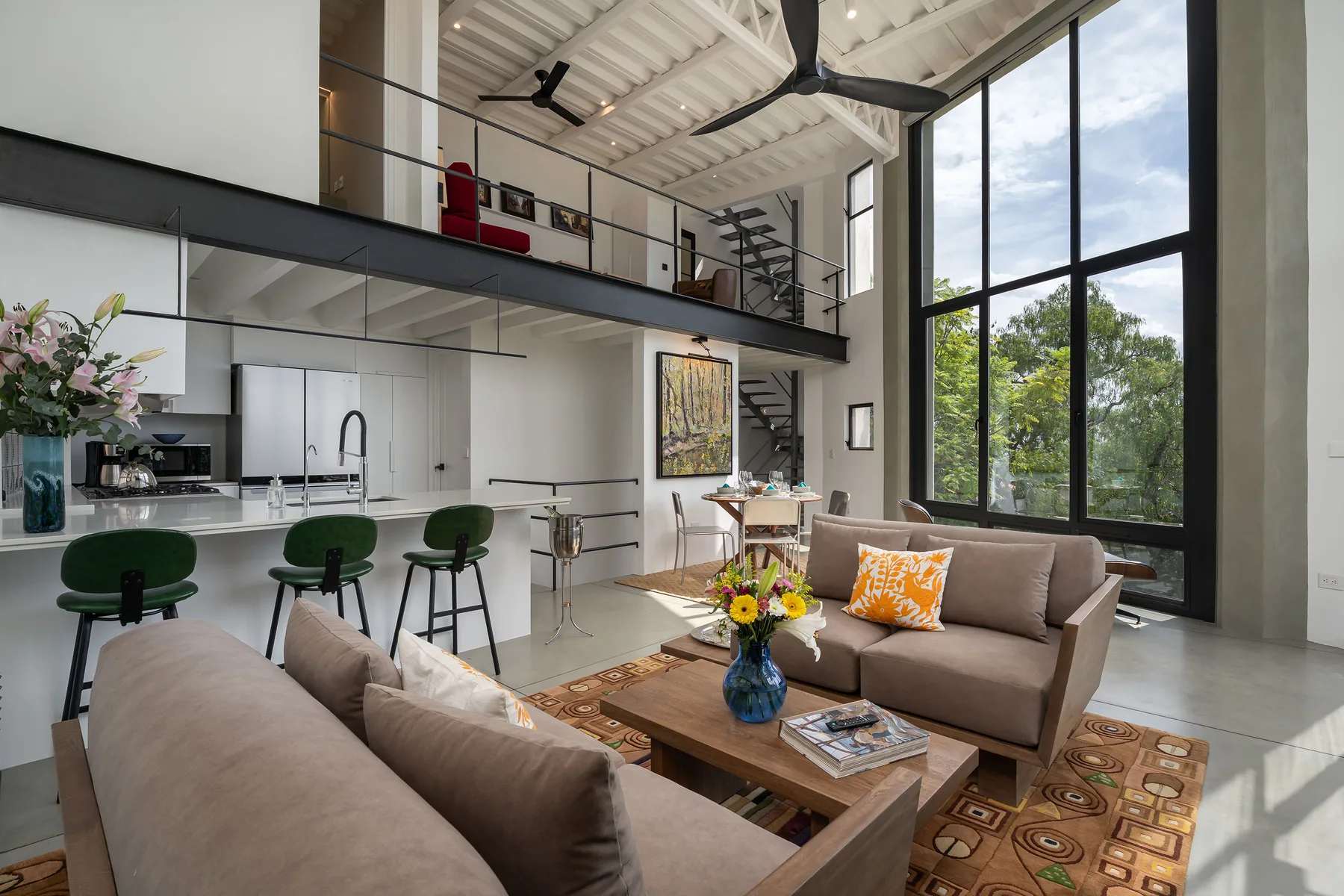 A bright double-height living room with seating beside tall windows.