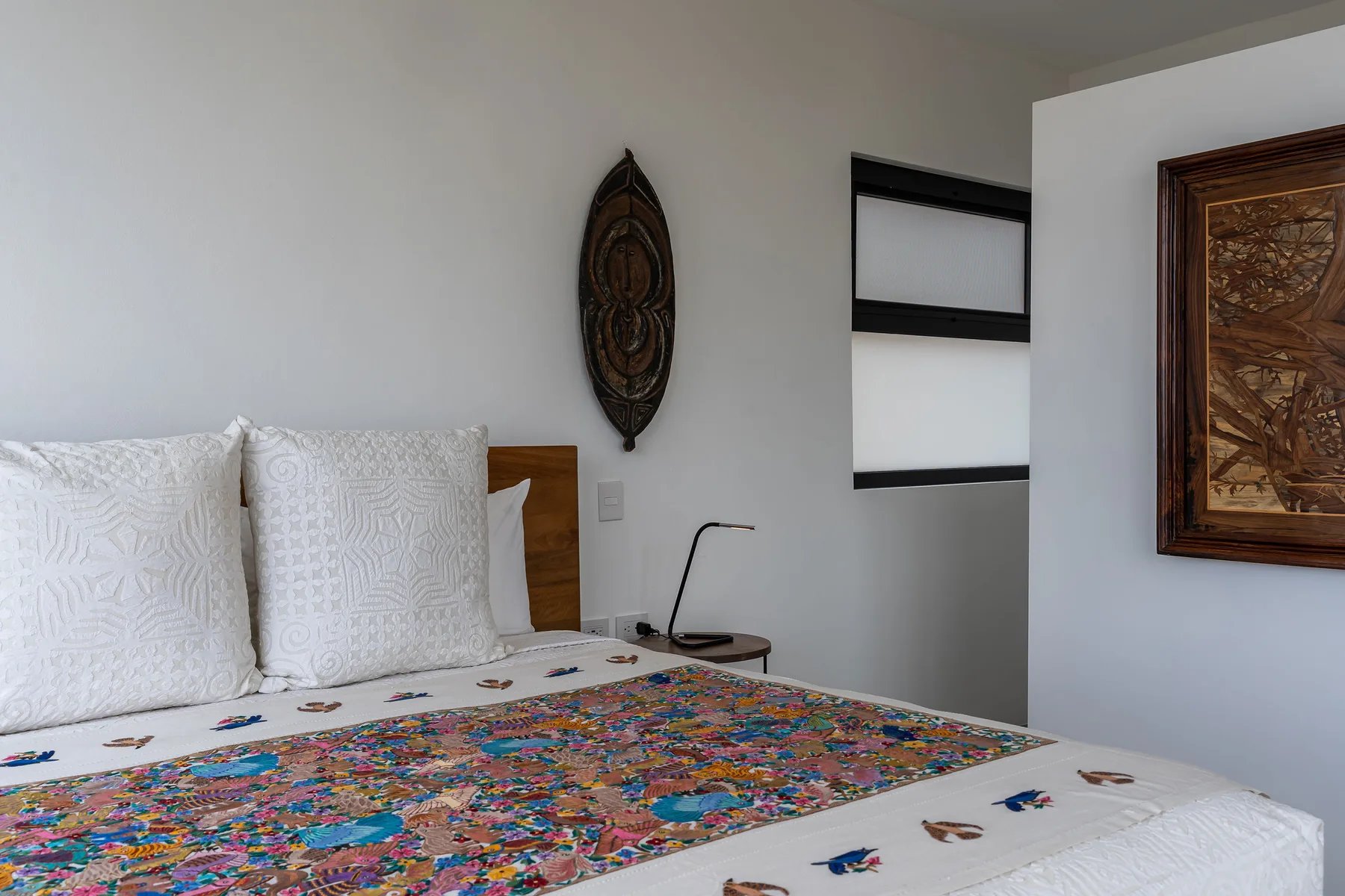A bedroom with a bed covered by a colorful patterned quilt.