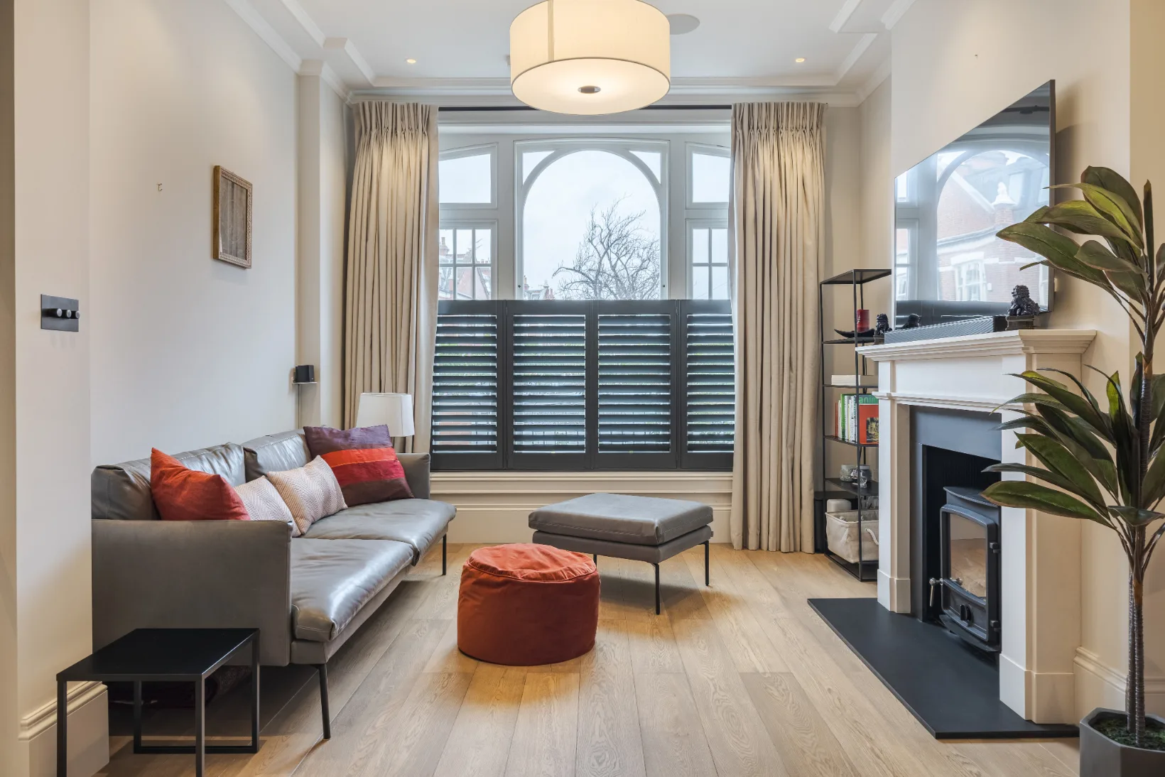 Una sala de estar luminosa con asientos, una chimenea y grandes ventanas.