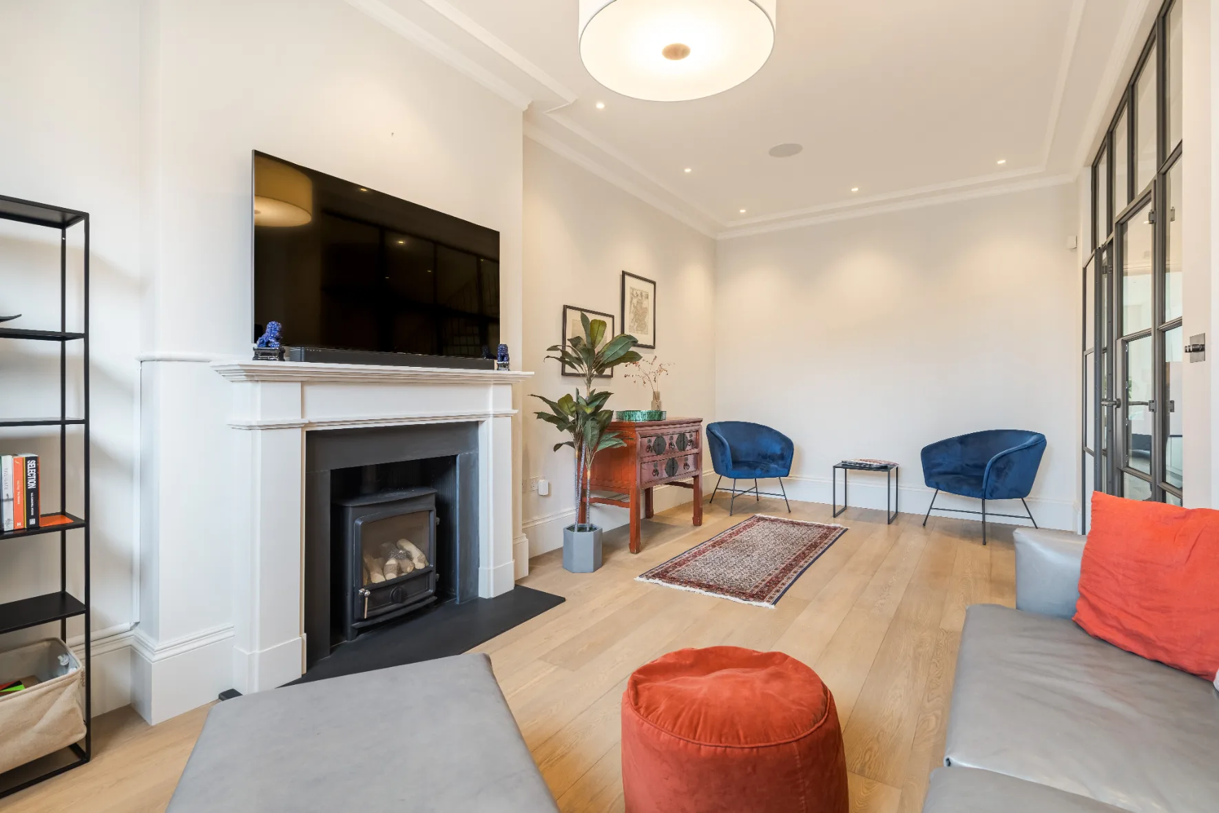 Una sala luminosa con chimenea, asientos y un televisor.