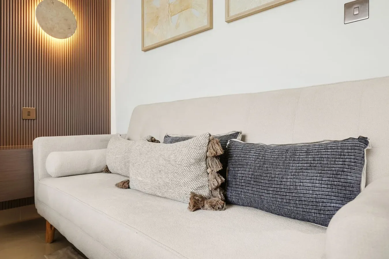 Una sala de estar con un sofá claro y cojines decorativos.