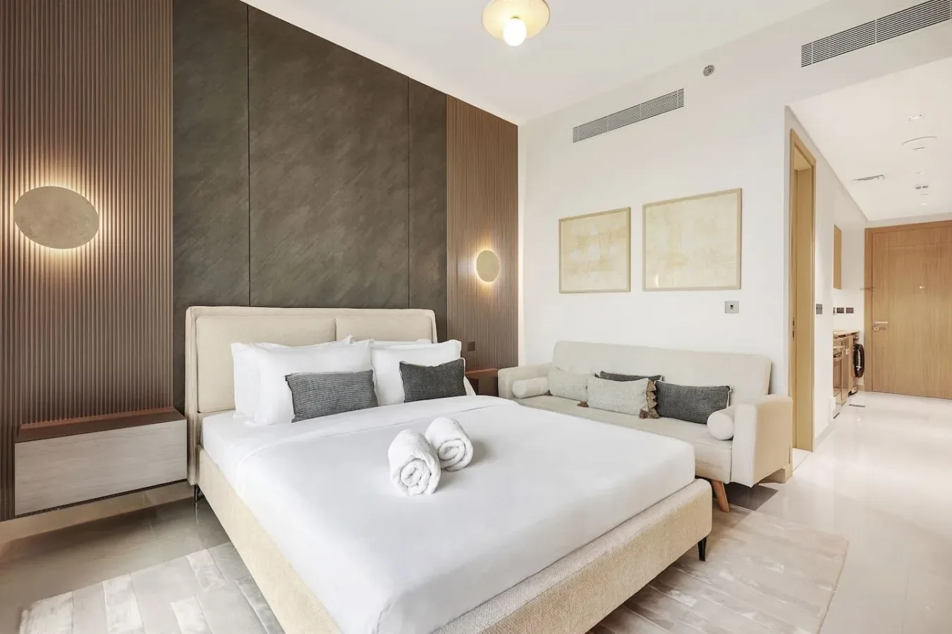 Un dormitorio luminoso con una cama grande y una zona de estar al lado.