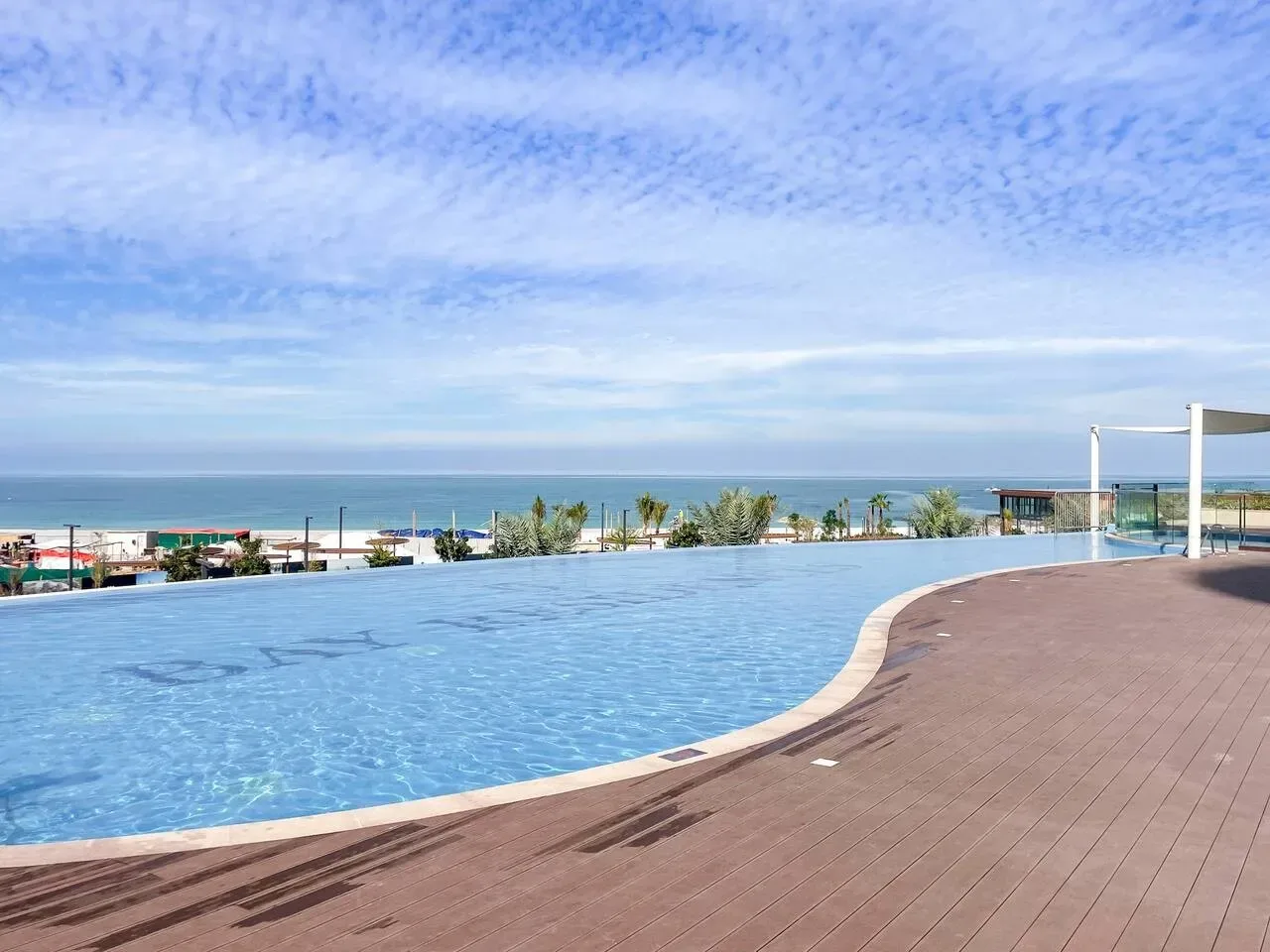 Una piscina tiene vistas al mar junto a una amplia terraza de madera.