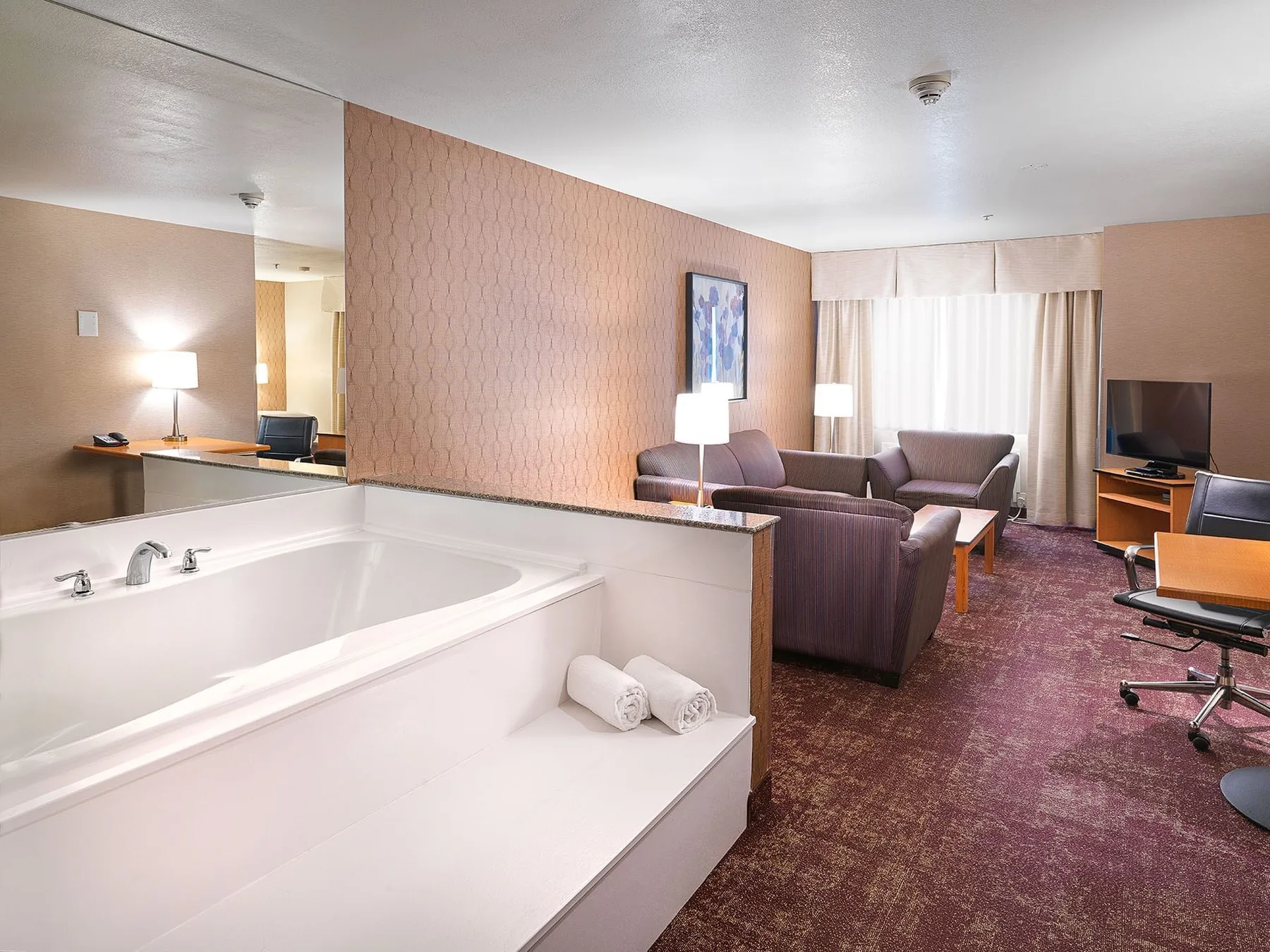Habitación de hotel con bañera grande, zona de estar y televisión