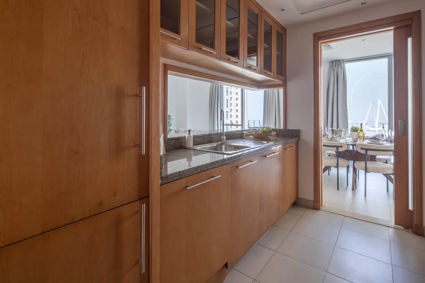 Una cocina con gabinetes de madera y una encimera da a un comedor luminoso.