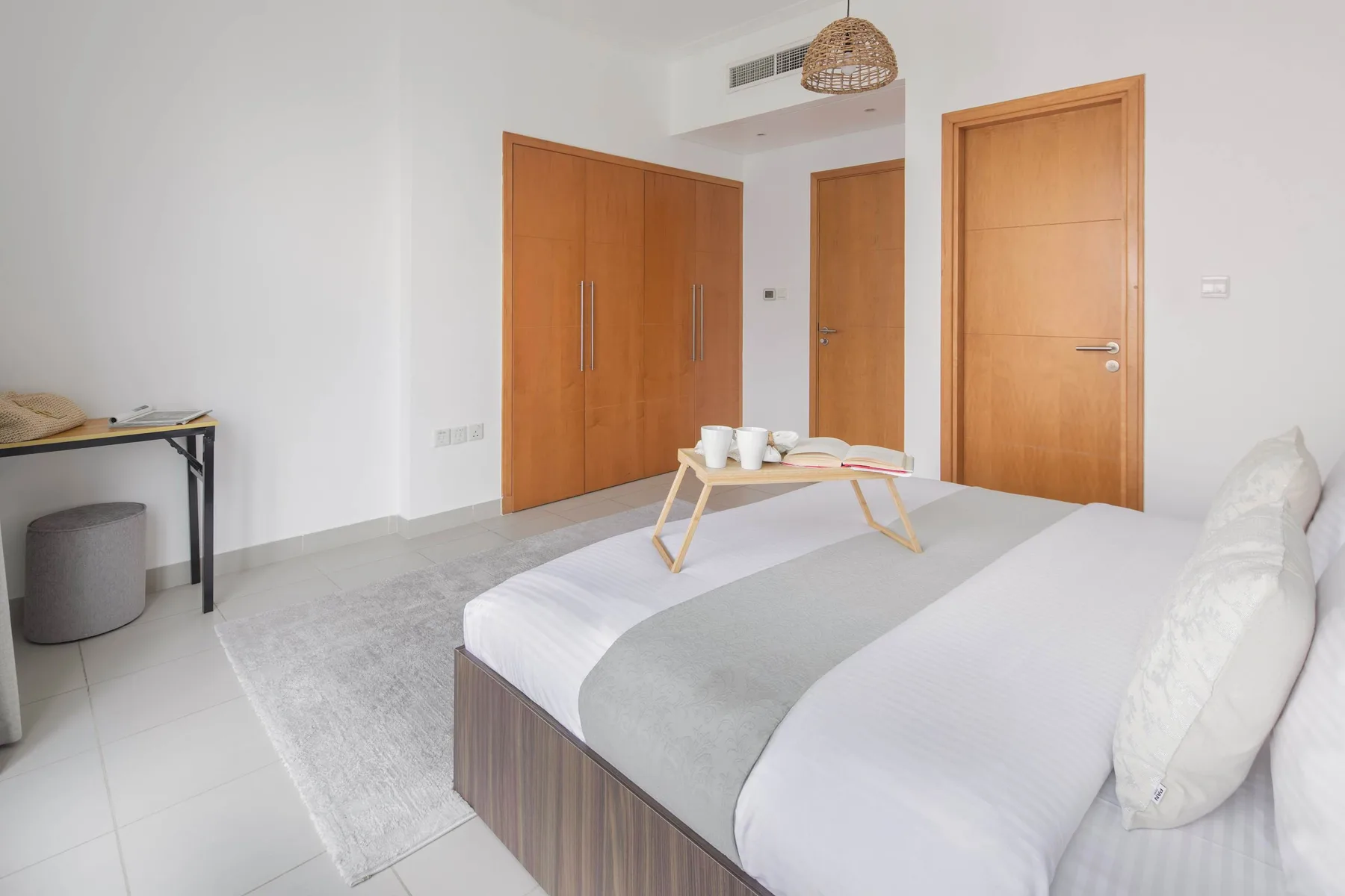 Un dormitorio luminoso con una cama y una mesita con tazas.