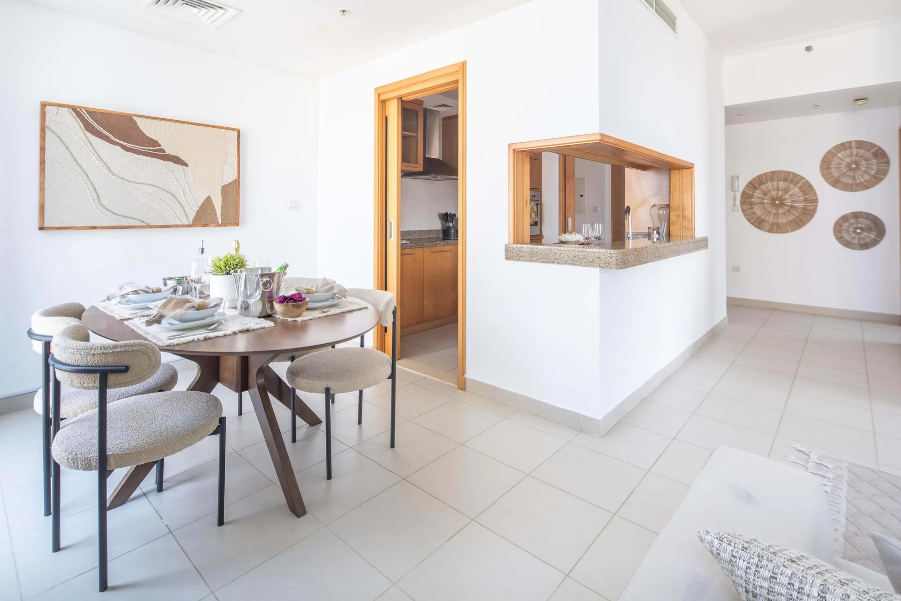 Un comedor luminoso con la mesa puesta junto a una barra de cocina.