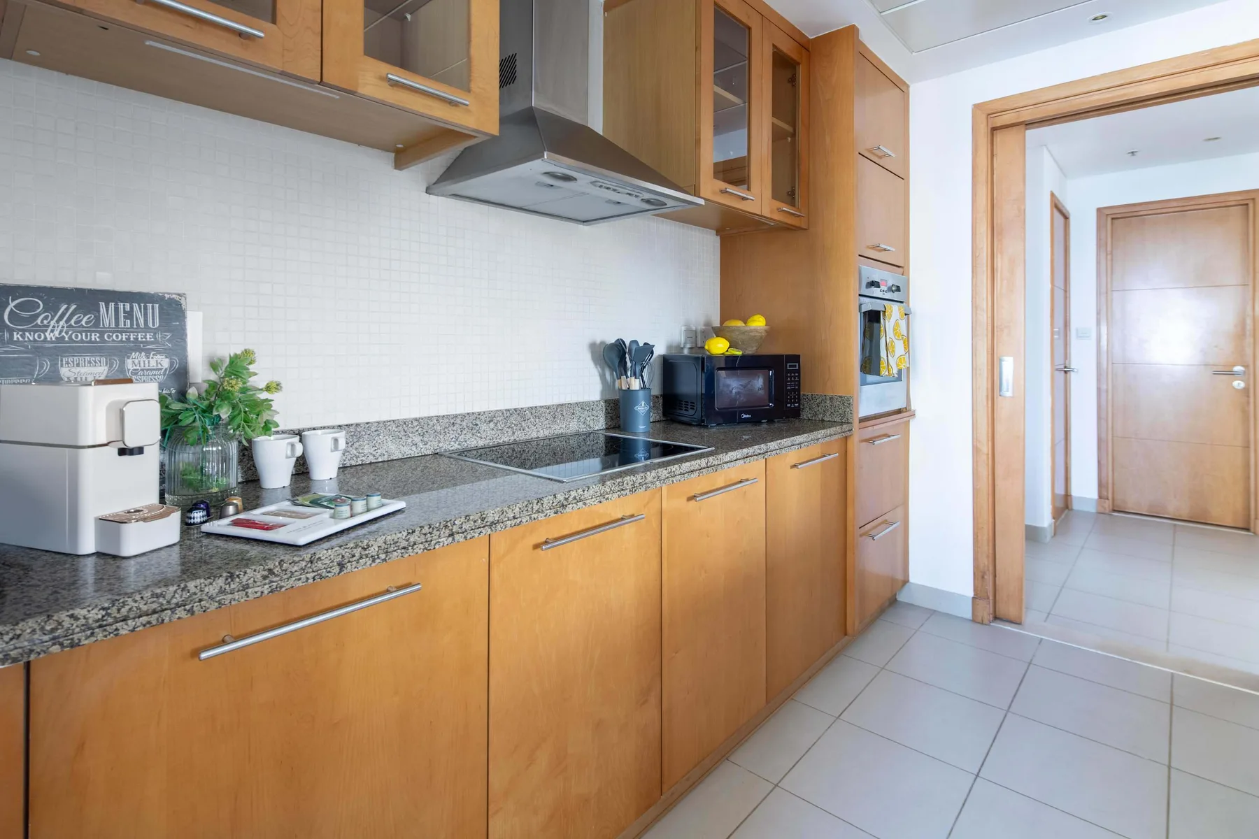 Una cocina con gabinetes de madera, una encimera y una puerta al pasillo.