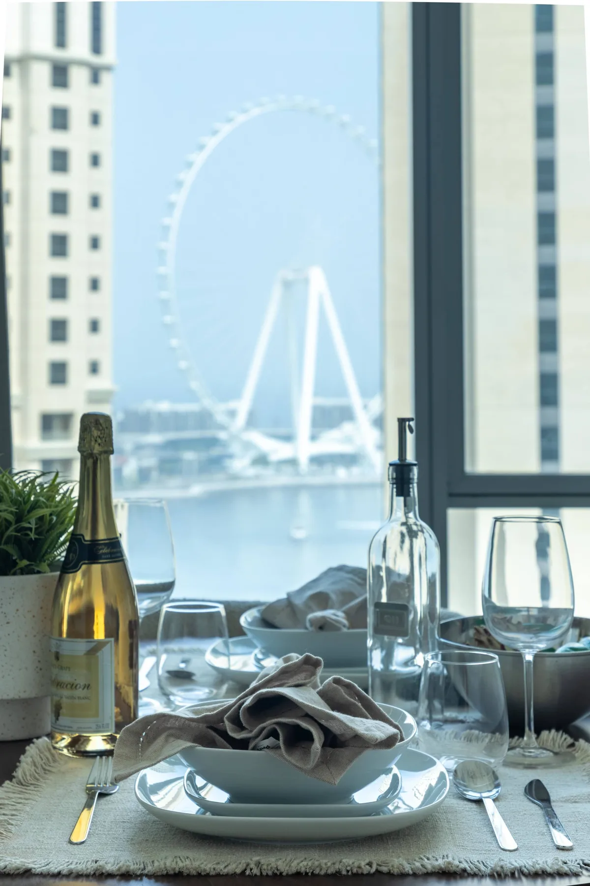Una mesa está puesta junto a una ventana con vista a una gran rueda de observación.