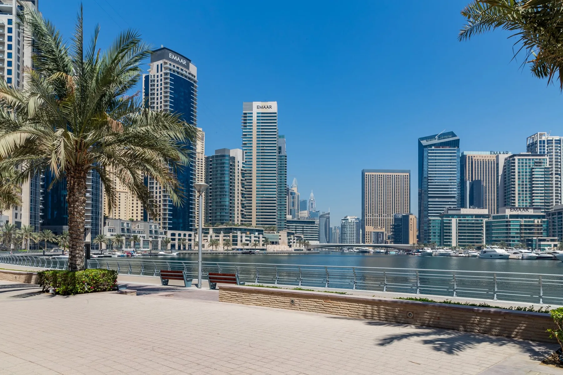Un paseo junto al agua da a una marina y a un horizonte de edificios altos.