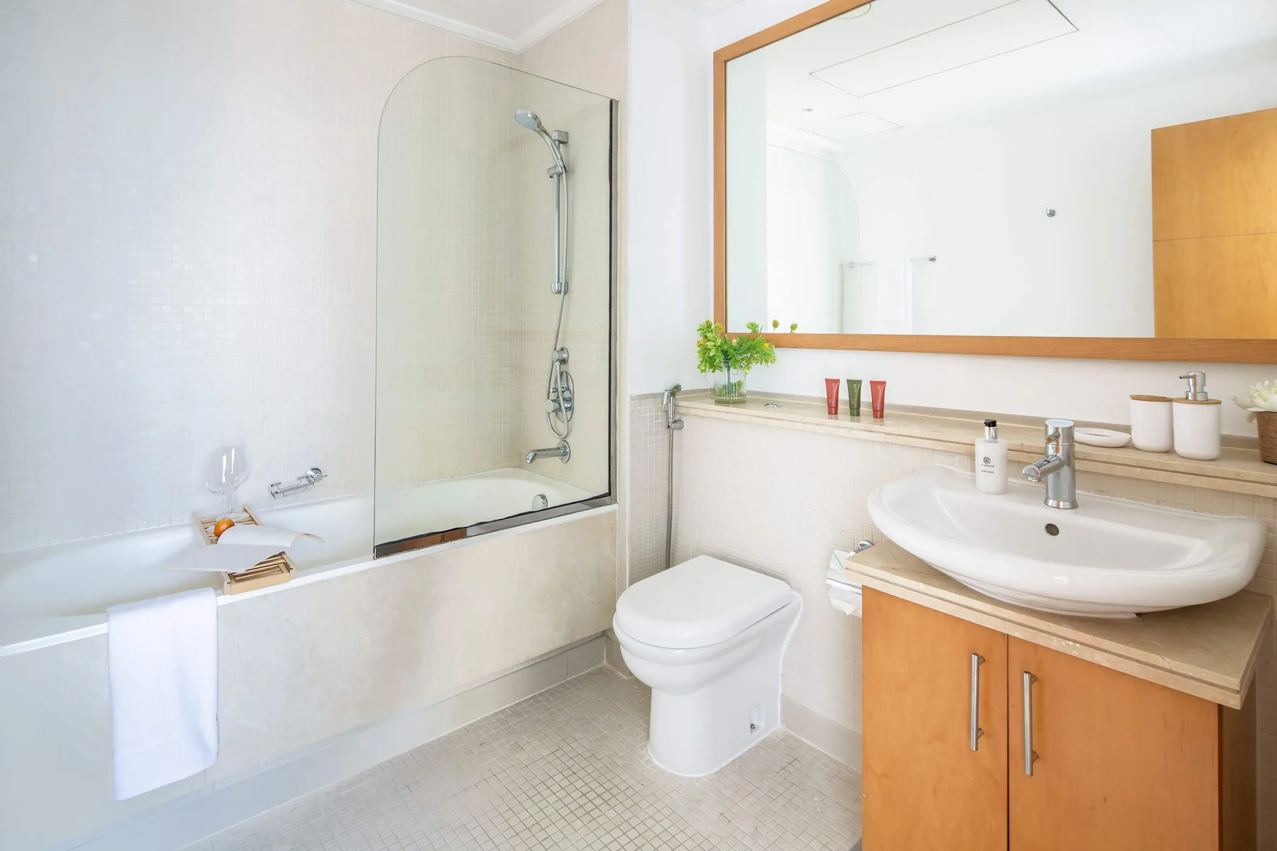 Un baño luminoso con bañera, inodoro y lavabo bajo un espejo grande.