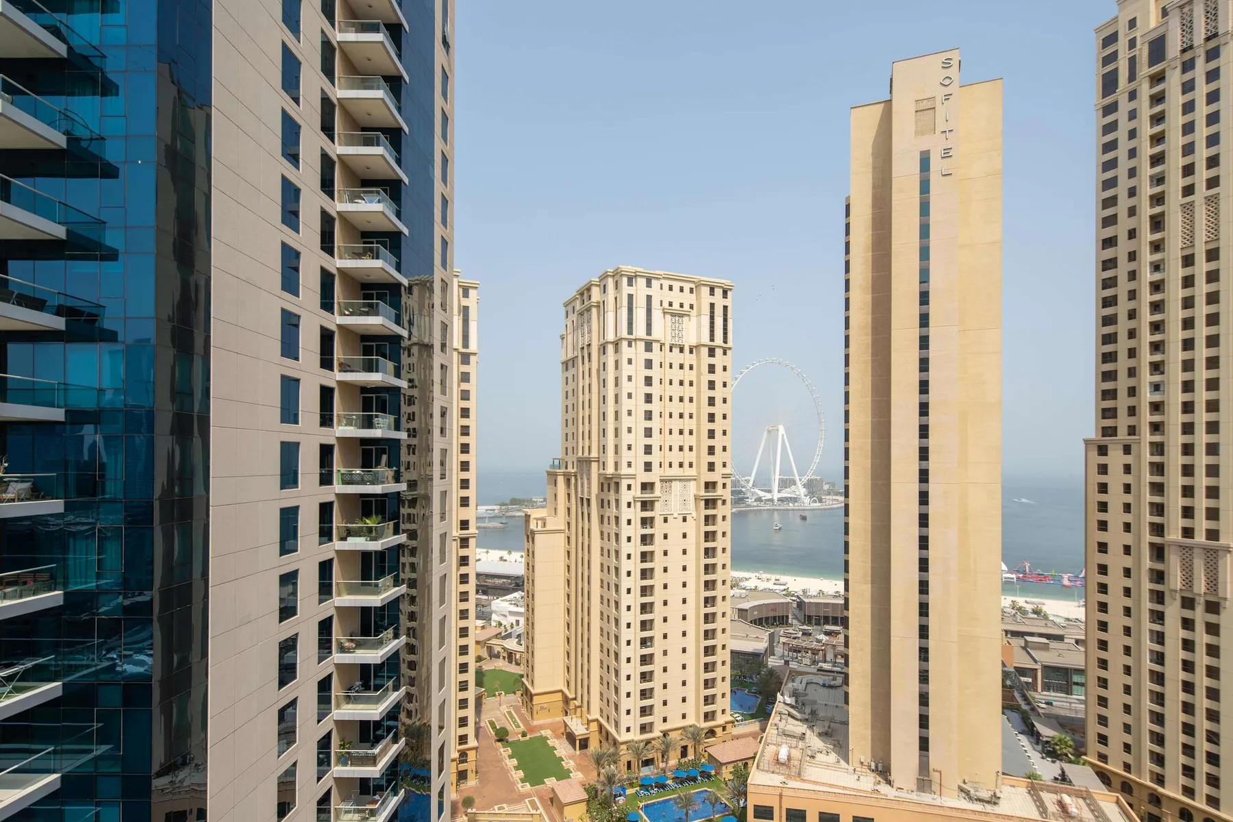 El horizonte urbano se alza junto al paseo marítimo, con edificios altos y una rueda emblemática a lo lejos.