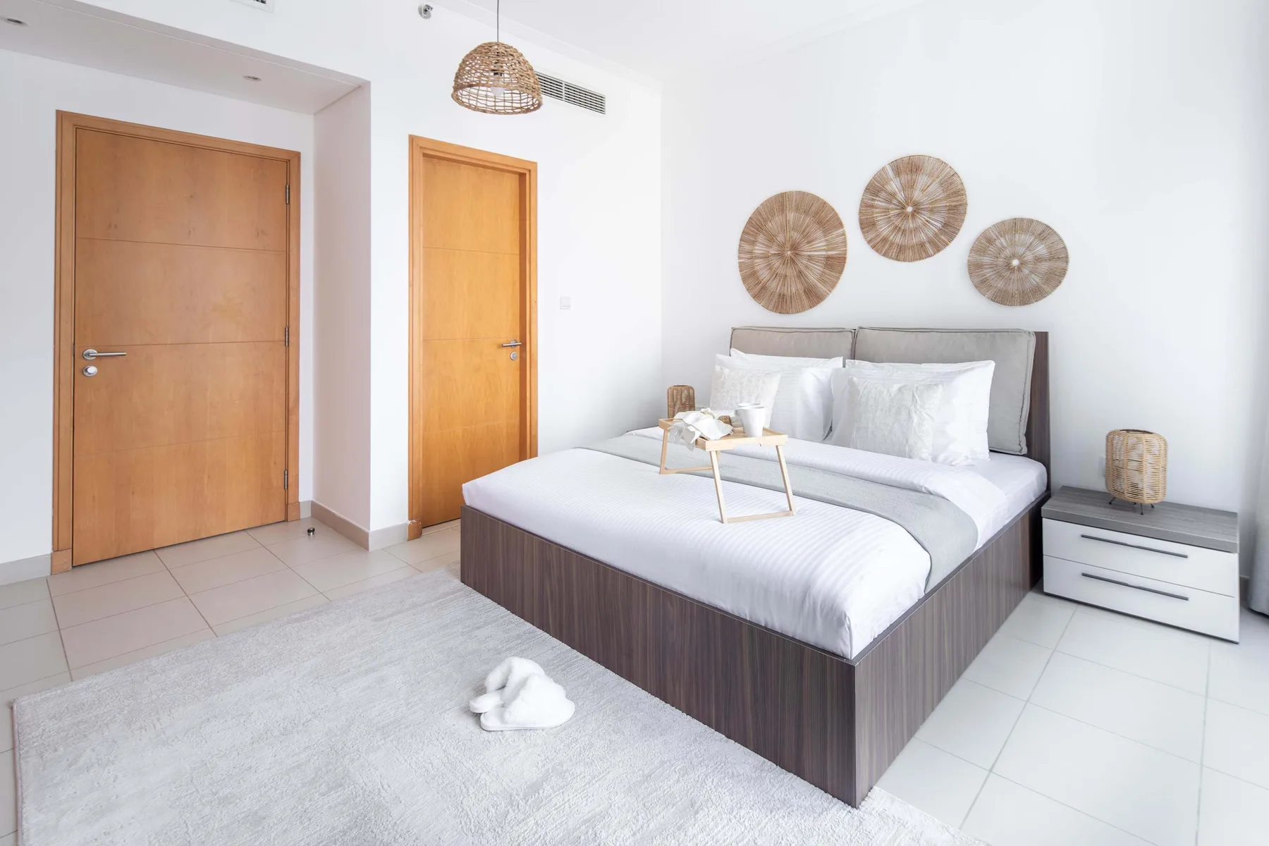 Un dormitorio luminoso con una cama grande, ropa de cama clara y adornos tejidos en la pared.