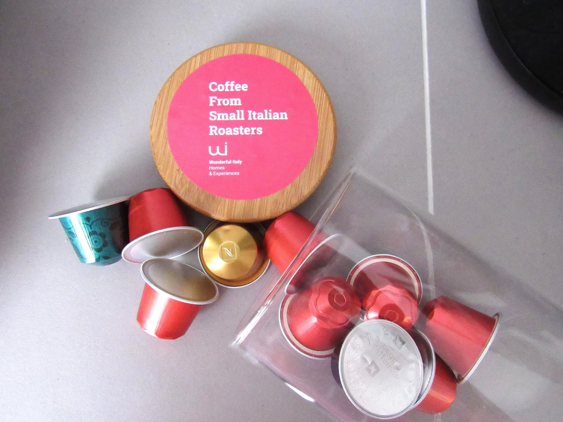 Coffee capsules and a round tin are arranged on a tiled counter.
