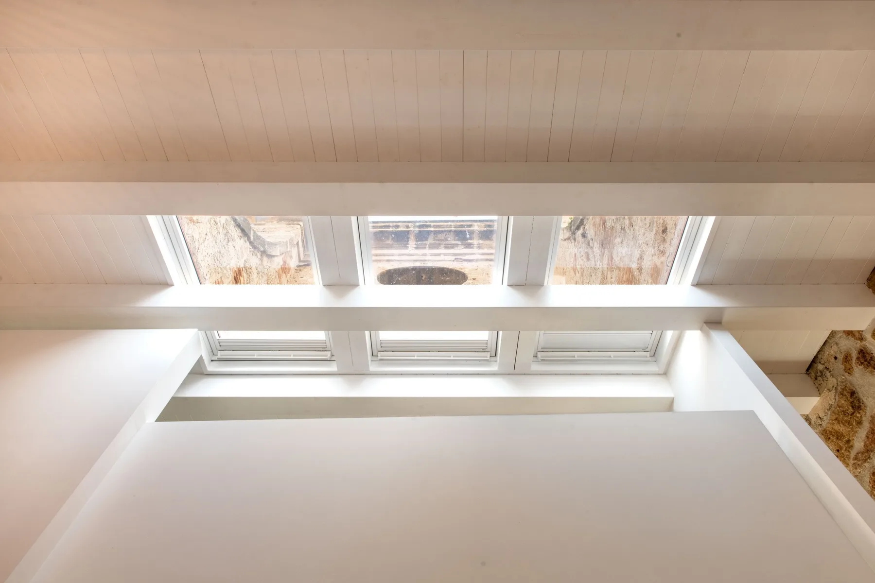 A bright interior view shows a large window above a plain white wall.