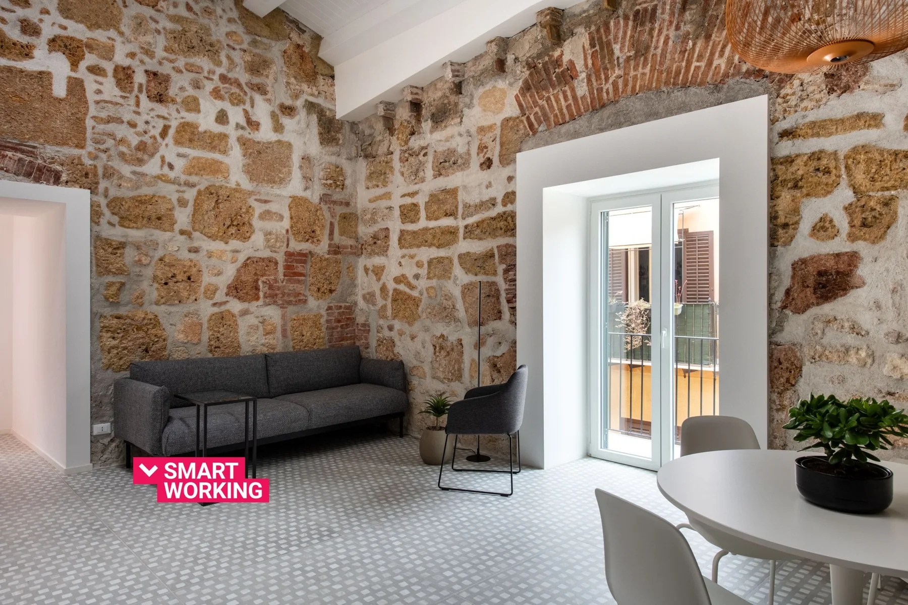 A stone-walled sitting room with a dark sofa and a round dining table.
