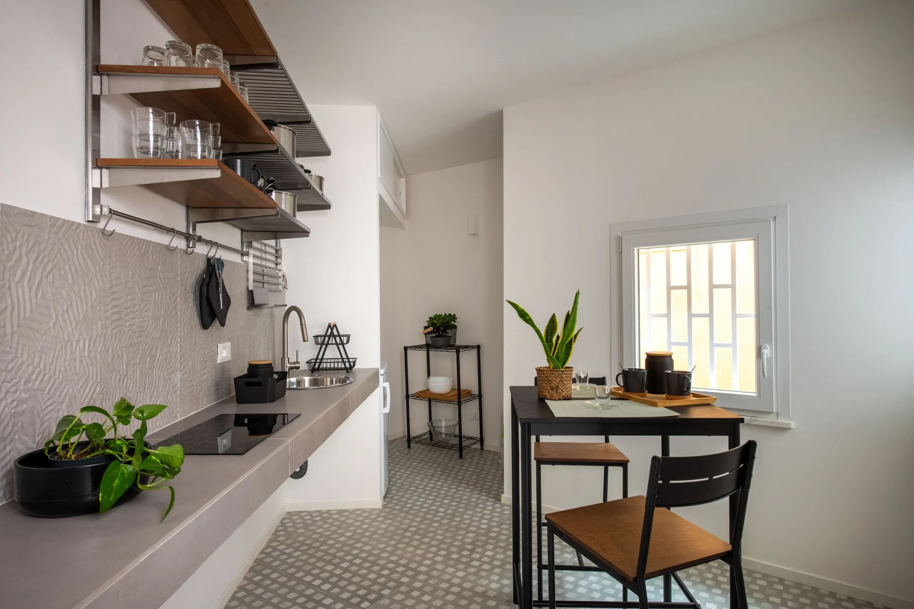 A compact kitchen with a countertop and a small dining table beside the window.