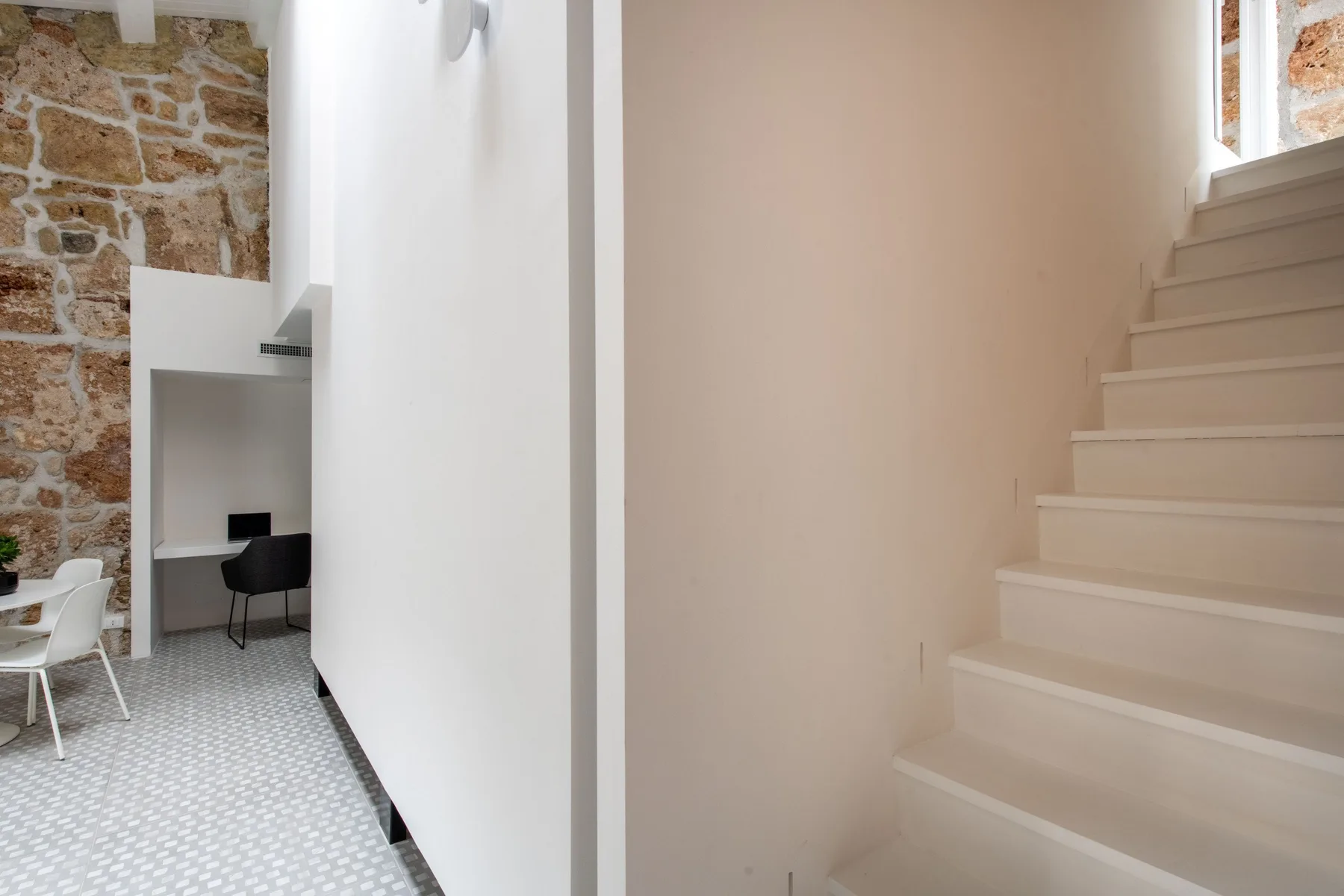 A bright interior hallway connects a tiled workspace with a staircase.