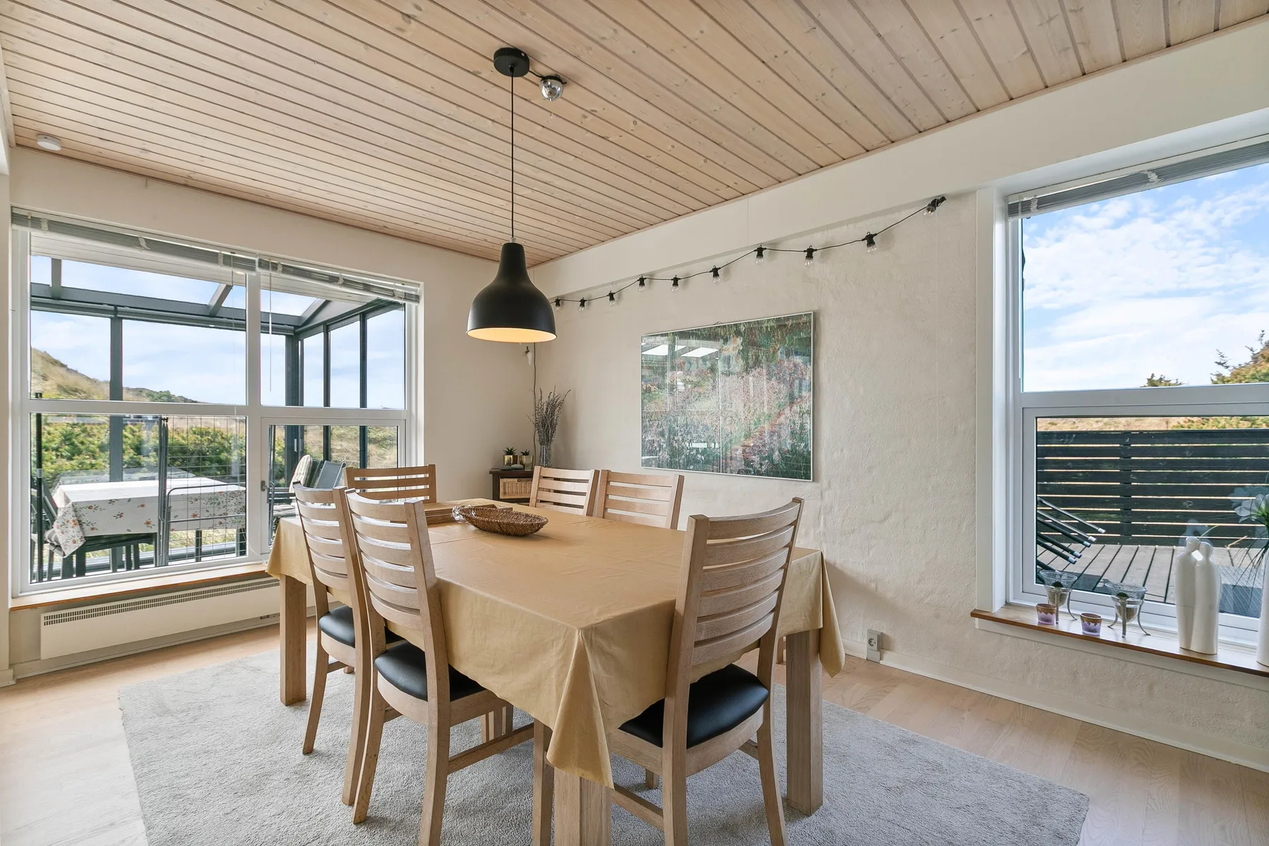 Comedor con una mesa grande y ventanas que dan a una terraza exterior.