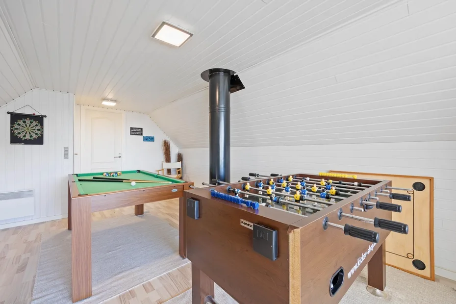 Una sala de juegos con futbolín y mesa de billar.