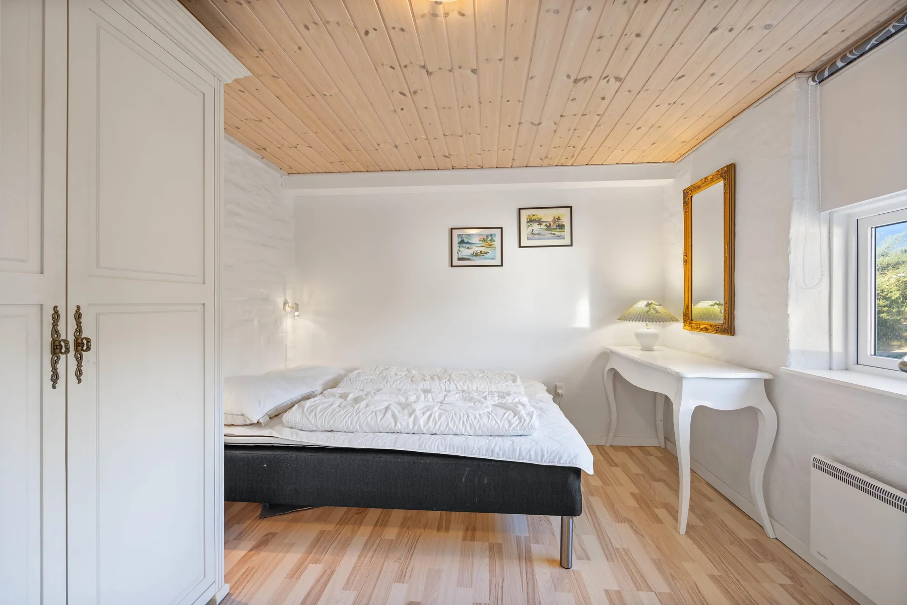Un dormitorio con una cama y un escritorio junto a la ventana.