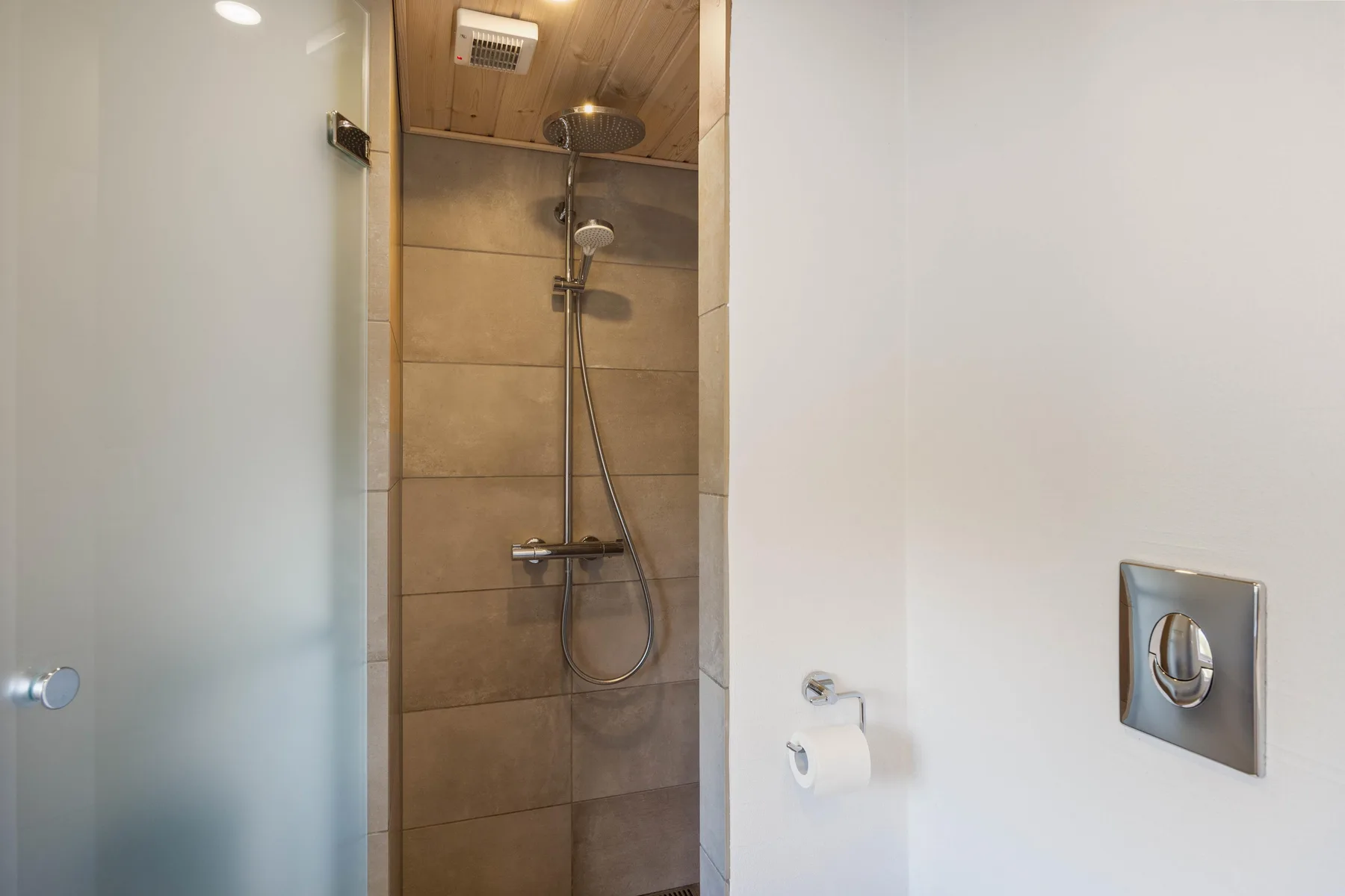Una ducha de baño con paredes de azulejos y techo de madera.