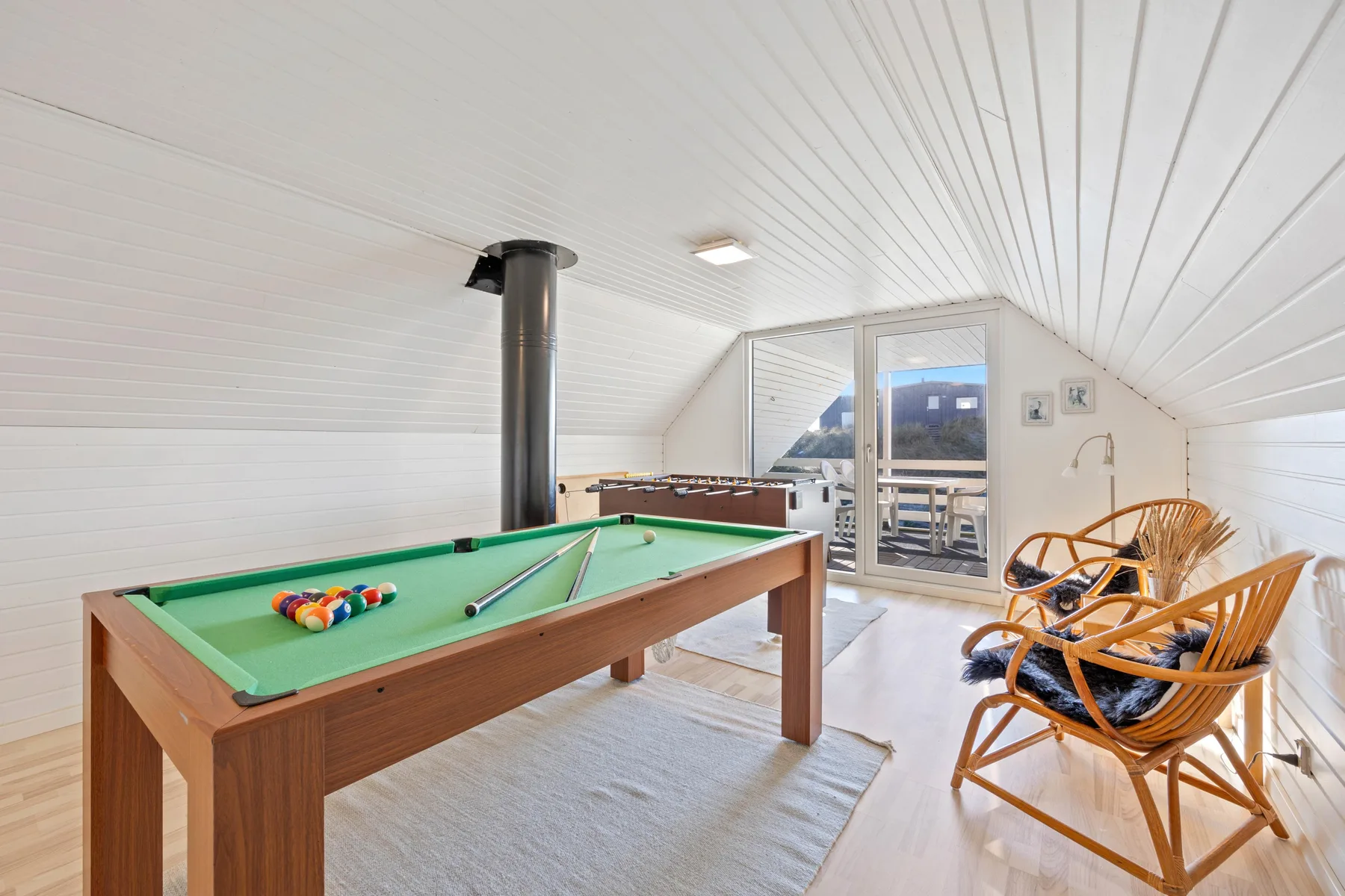 Una luminosa sala de juegos con una mesa de billar y asientos junto a puertas de vidrio.