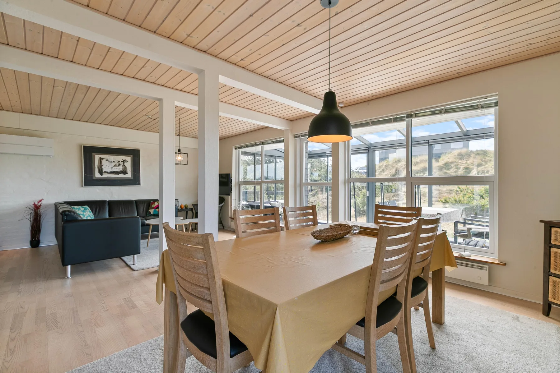 Un comedor luminoso con una mesa de madera junto a grandes ventanas.