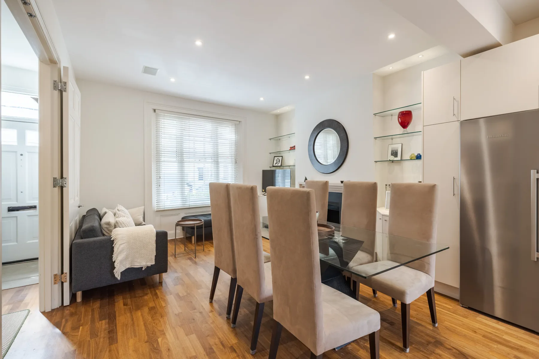 A bright open-plan living and dining area with a glass dining table.