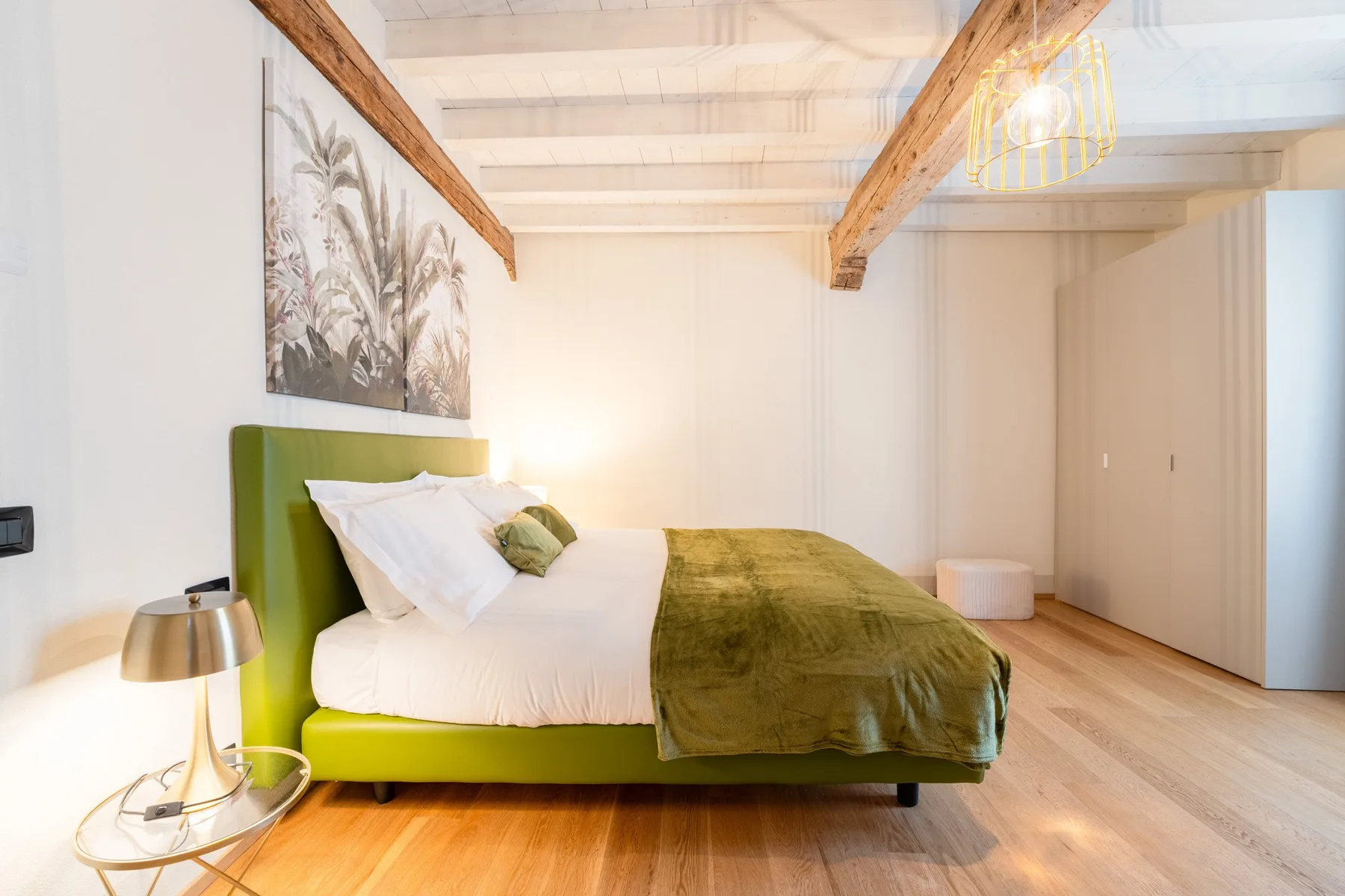 Un dormitorio con una cama vestida de blanco y una manta verde.