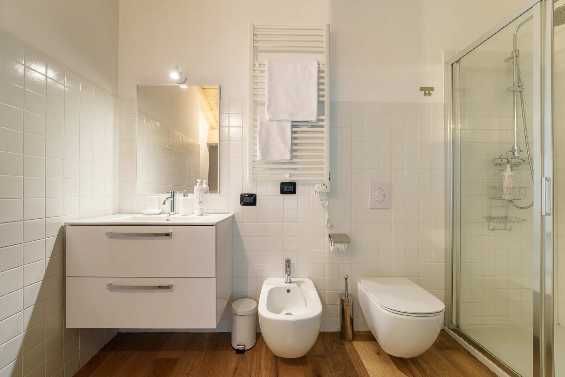 Un baño alicatado con lavabo, inodoro y ducha de vidrio.