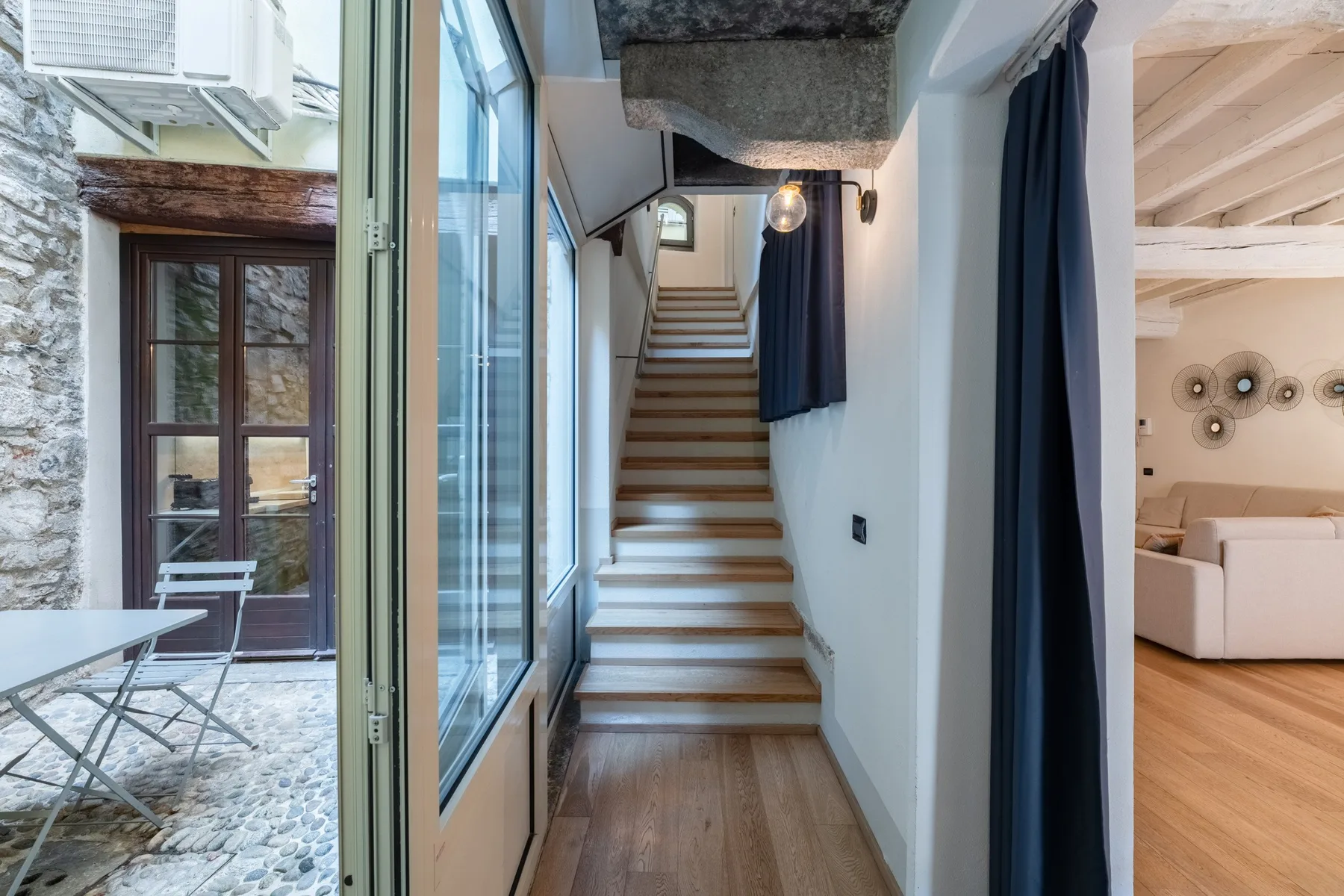 Un pasillo interior estrecho con una escalera y ventanas altas.