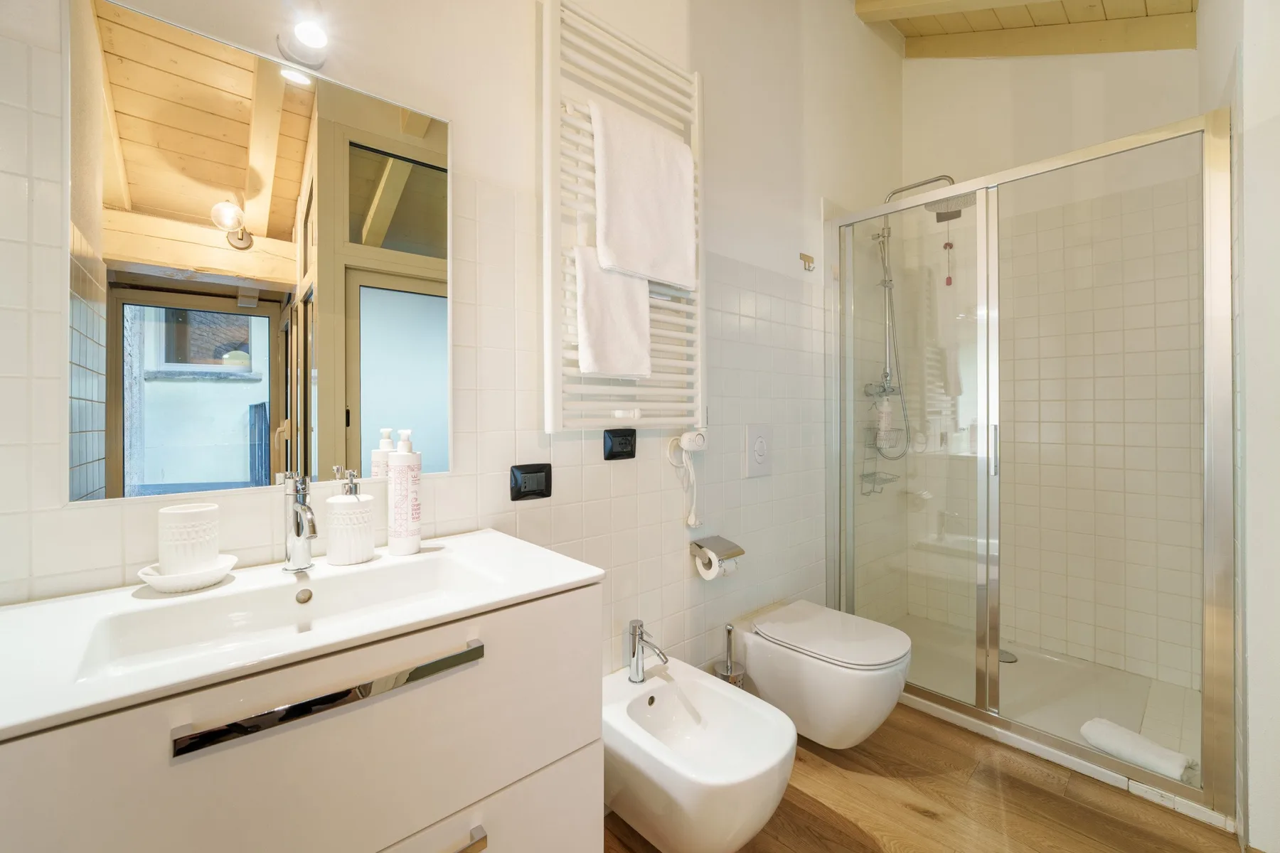 Un baño luminoso con lavabo, inodoro, bidé y ducha de cristal.