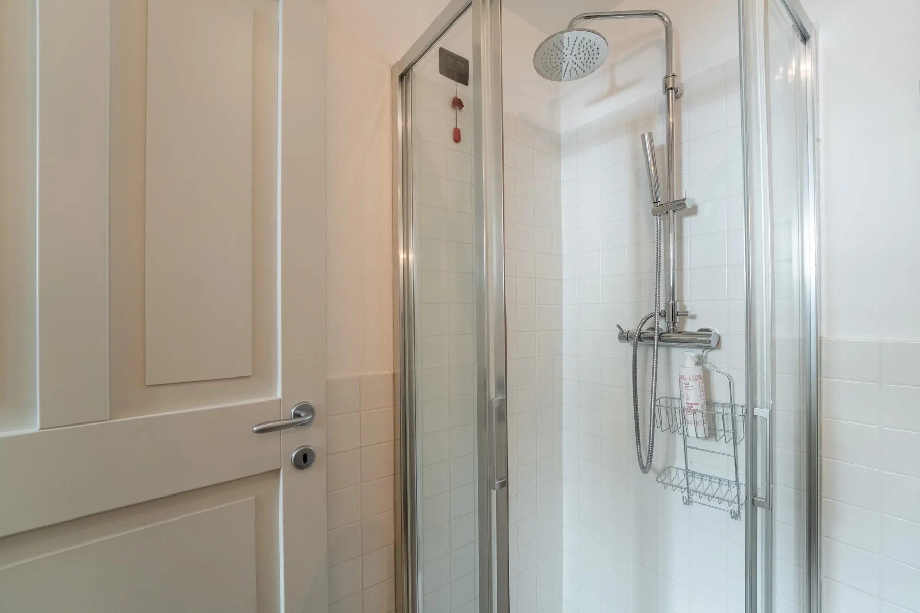 Una ducha de baño con azulejos, ducha de mano y paneles de vidrio.