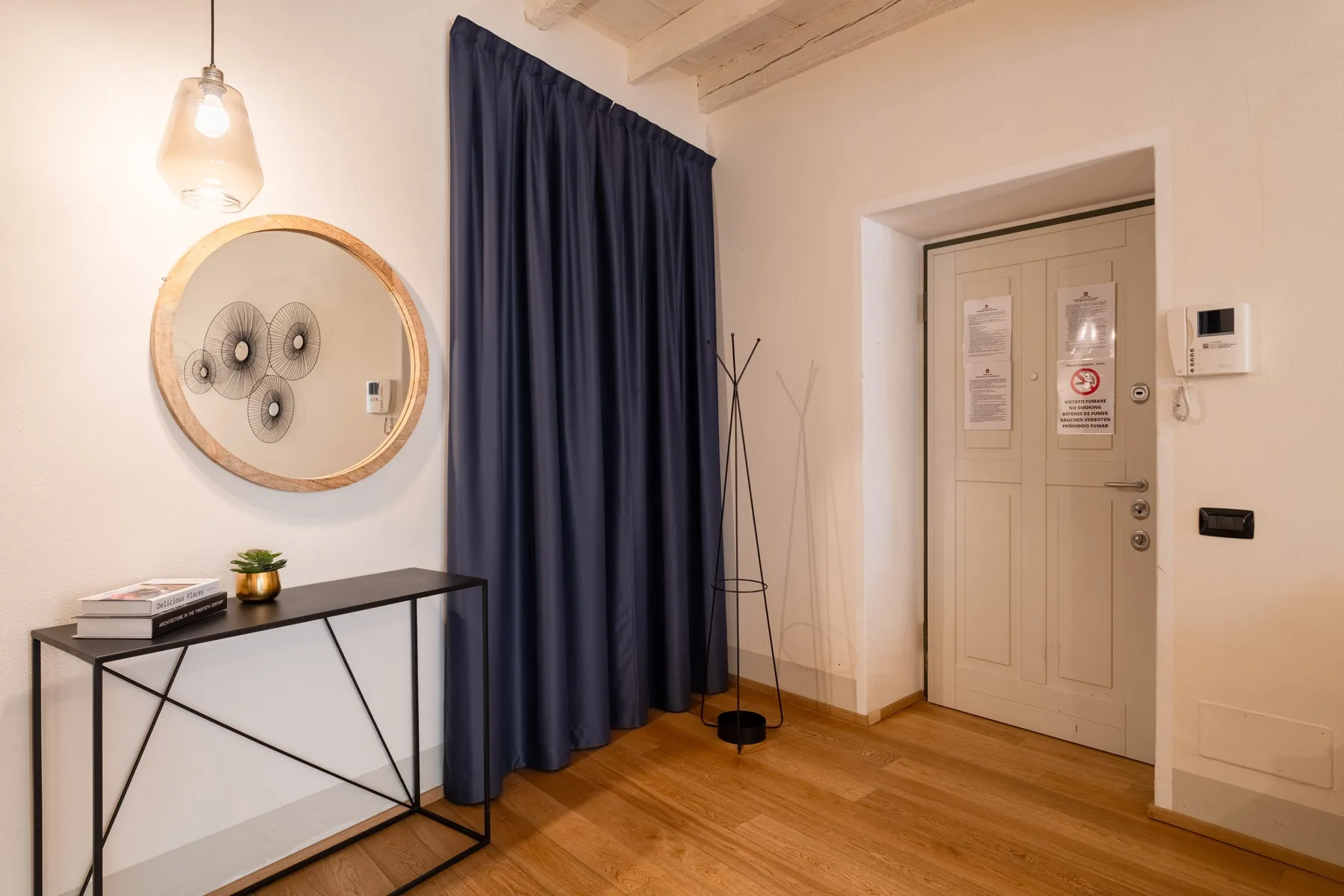 Una entrada con una ventana cubierta por cortinas, una mesa consola y una puerta cerrada.