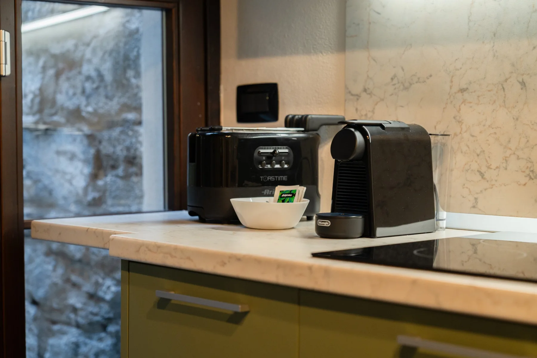 Una encimera de cocina con una cafetera y un cuenco junto a la ventana.